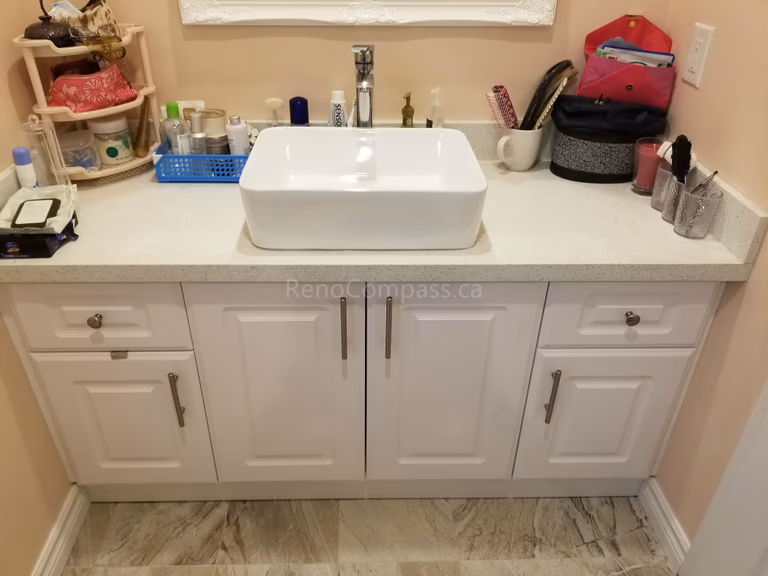 This Markham bathroom renovation includes a newly installed custom vanity with a modern countertop vessel sink and upgraded faucet. The clean white cabinetry provides ample storage while complementing the new floor tiles and overall bathroom design. The refreshed vanity area enhances both functionality and style, creating a bright, organized, and contemporary bathroom space for daily use.