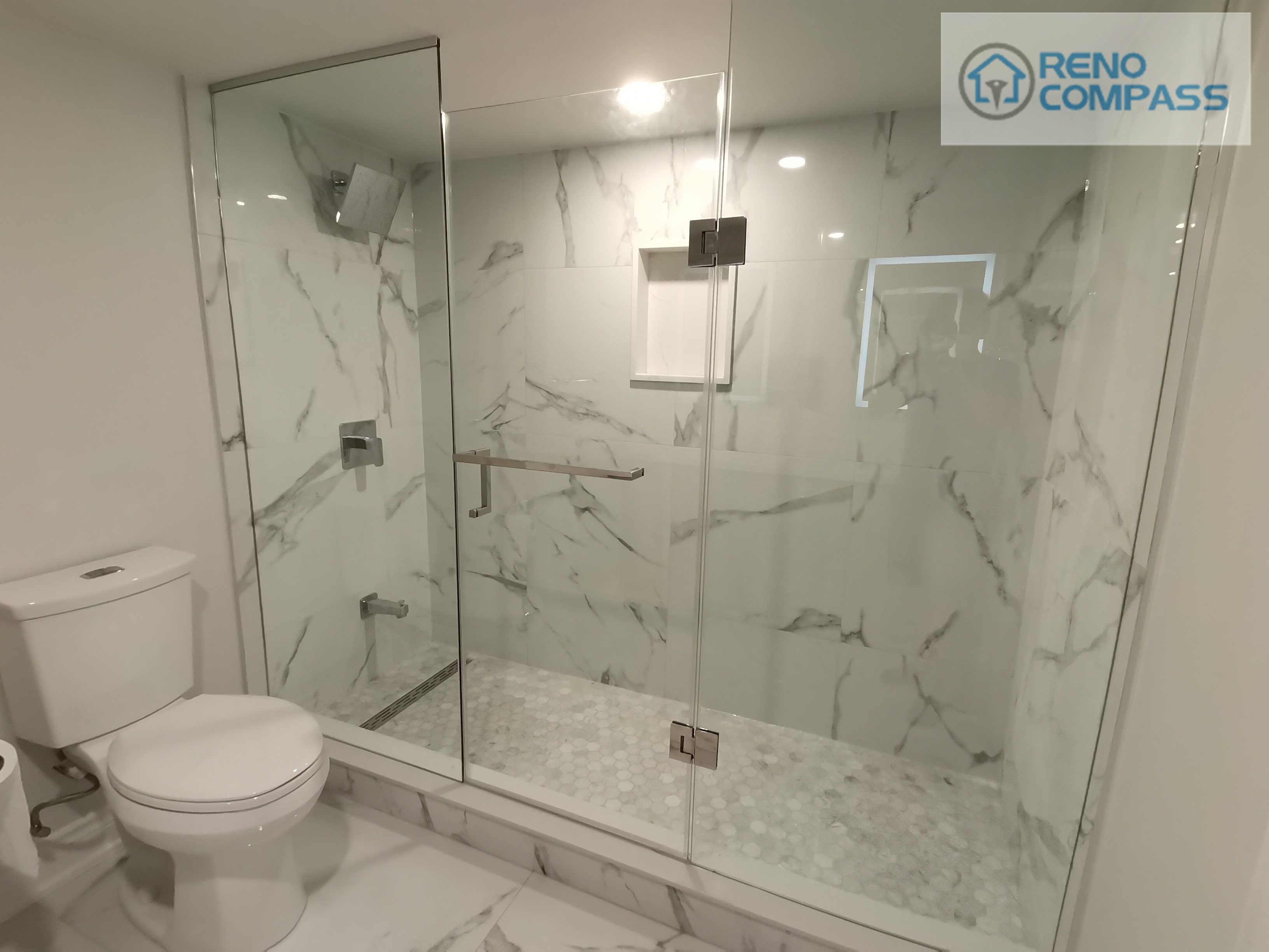 This Woodbridge basement bathroom renovation showcases a spacious frameless glass shower with marble-look wall tiles and a built-in niche for everyday storage. The clean glass enclosure enhances natural light flow while maintaining a sleek, modern appearance, creating a functional and elegant shower space designed for long-term use.