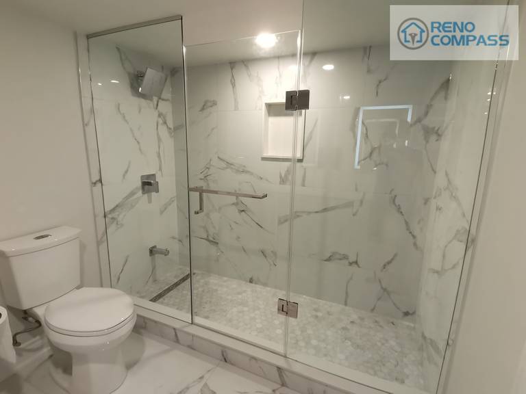 This Woodbridge basement bathroom renovation showcases a spacious frameless glass shower with marble-look wall tiles and a built-in niche for everyday storage. The clean glass enclosure enhances natural light flow while maintaining a sleek, modern appearance, creating a functional and elegant shower space designed for long-term use.