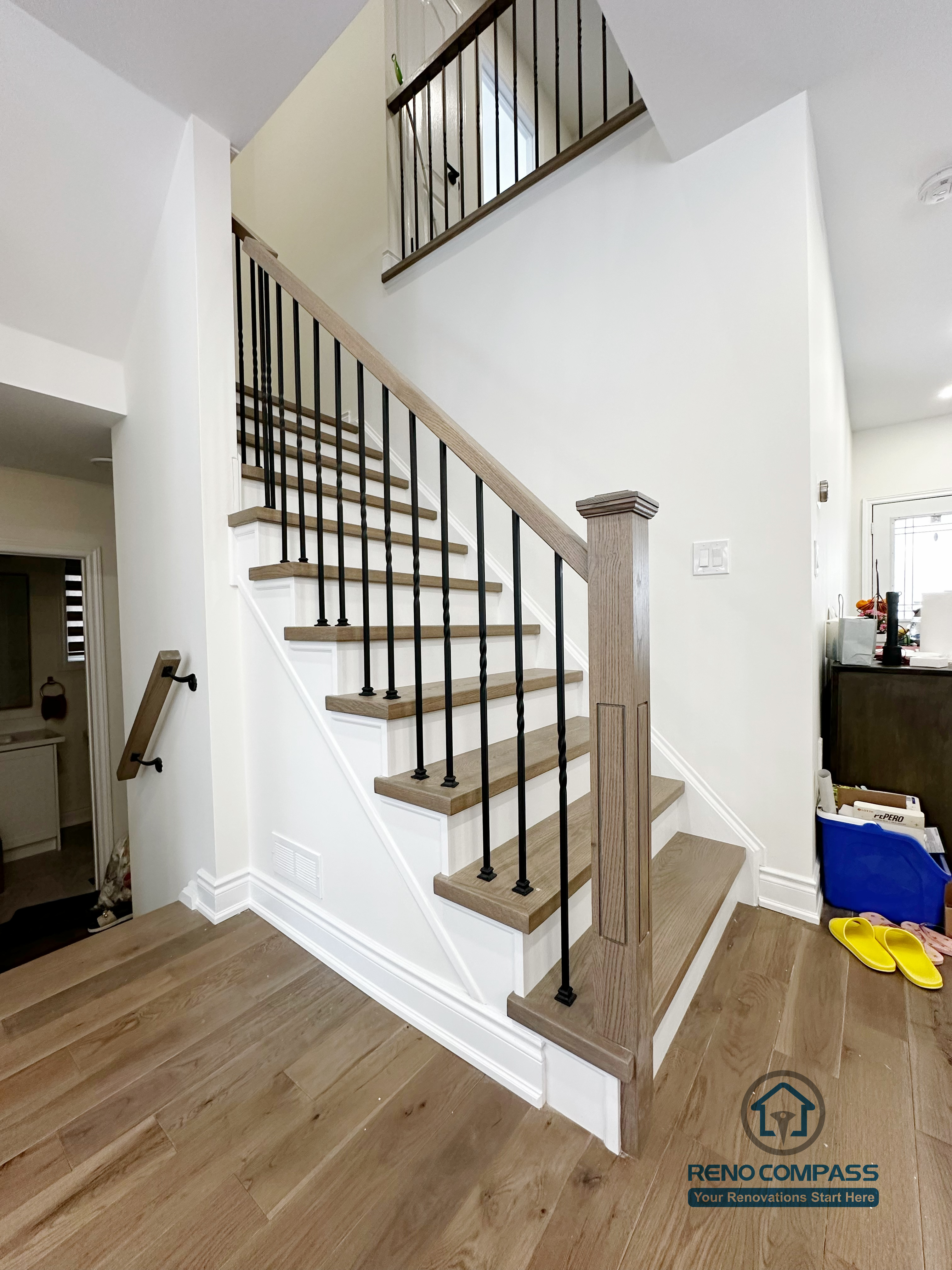 Interior renovation in Markham featuring a custom hardwood staircase with wood treads, square newel posts, and black metal balusters. The staircase design enhances vertical flow, safety, and visual continuity within the open-concept main floor.