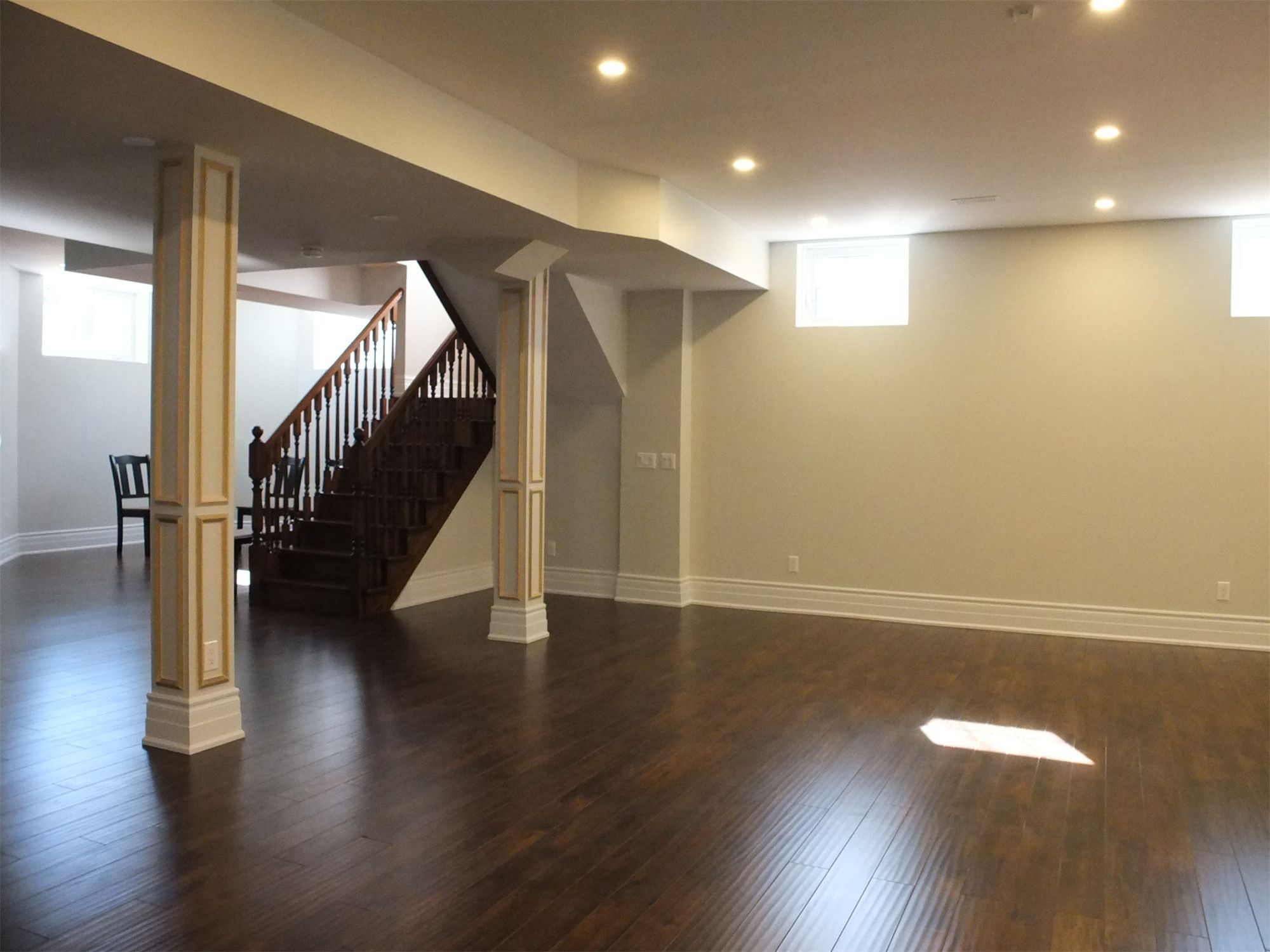 This Richmond Hill basement renovation features a spacious open-concept layout with rich hardwood flooring, custom decorative columns, and modern recessed lighting. The upgraded staircase, neutral wall tones, and clean architectural details create a bright and functional living space ideal for family use and entertaining. Professionally finished to enhance comfort, durability, and home value.