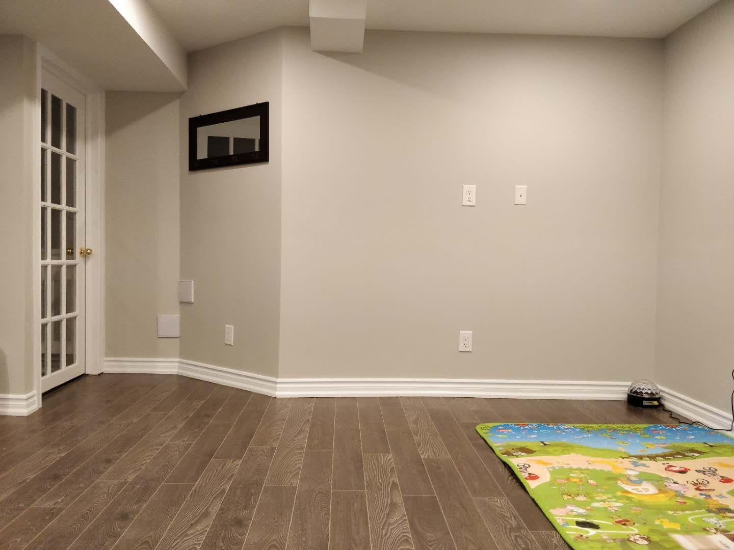 This image highlights the open-concept layout of a completed basement renovation in Scarborough. The space features newly installed hardwood flooring, neutral-toned walls, recessed pot lighting, and a structural support column seamlessly integrated into the design. The clean and spacious layout enhances functionality, making it ideal for a recreation room, family living area, or entertainment space. Completed by Reno Compass Inc., this basement renovation reflects professional craftsmanship and thoughtful space planning for modern family living.