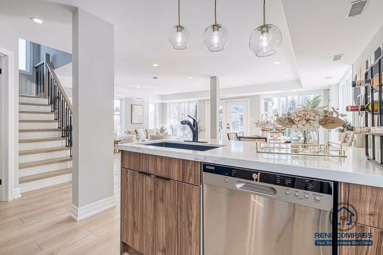 This Georgian interior renovation features a functional kitchen island with integrated appliances, pendant lighting, and seamless flow to the living and dining areas. Thoughtful layout and material selection reflect the quality of a Toronto renovation company.