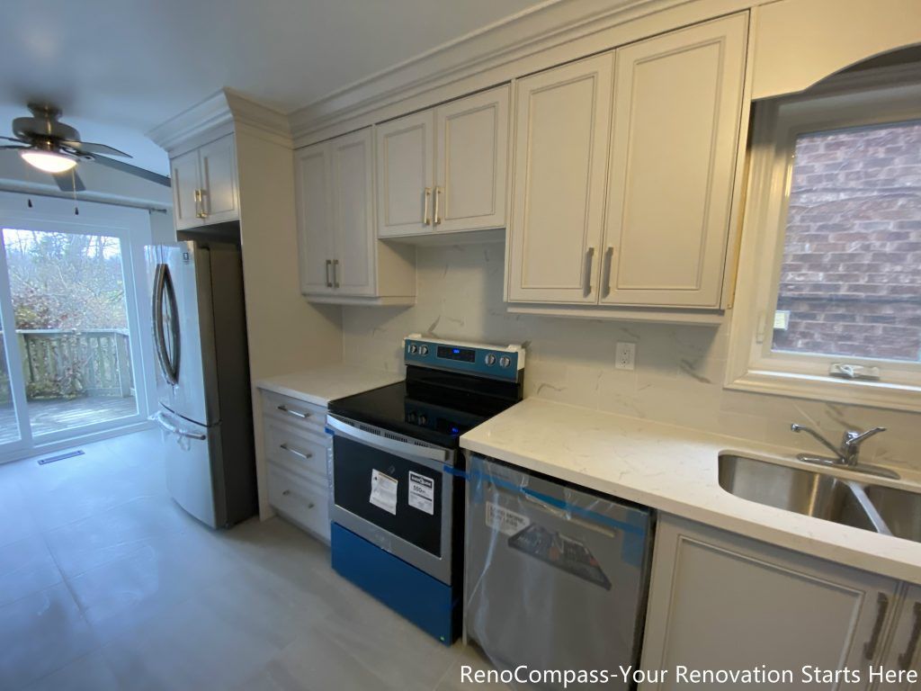 This Mississauga interior renovation showcases a modern kitchen layout featuring shaker-style cabinets, quartz countertops, and stainless steel appliances. The well-organized cooking and sink area is designed for efficiency and daily use, with clean lines, ample storage, and natural light from the window enhancing both functionality and visual balance. A practical and timeless kitchen renovation solution for family living.