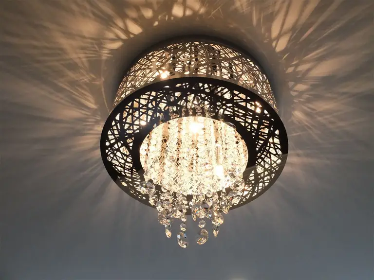 This Kleinburg interior renovation highlights a decorative crystal ceiling light fixture that adds elegance and visual texture to the room. The intricate metal frame and hanging crystal elements create beautiful light reflections across the ceiling, enhancing the ambiance of the space. This refined lighting detail complements the modern interior design while bringing a touch of luxury to the renovated home.