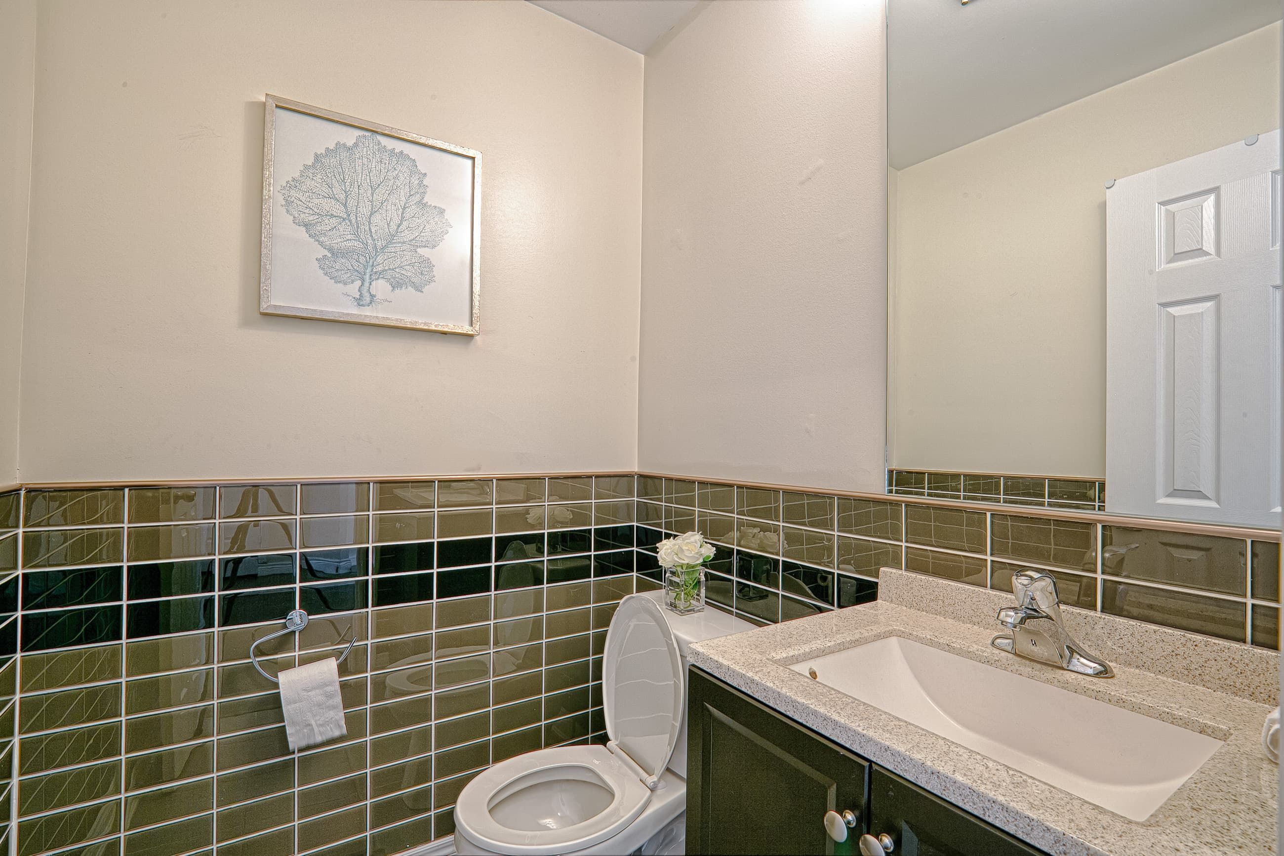 This modern bathroom renovation features a clean vanity design with a durable quartz countertop, contemporary sink, and large mirror to enhance brightness and space perception. The decorative horizontal tile detailing adds texture and visual interest while maintaining a sleek and neutral palette. Designed for both practicality and style, this bathroom upgrade reflects the craftsmanship of a professional Toronto renovation company delivering refined interior renovation solutions for modern homes.