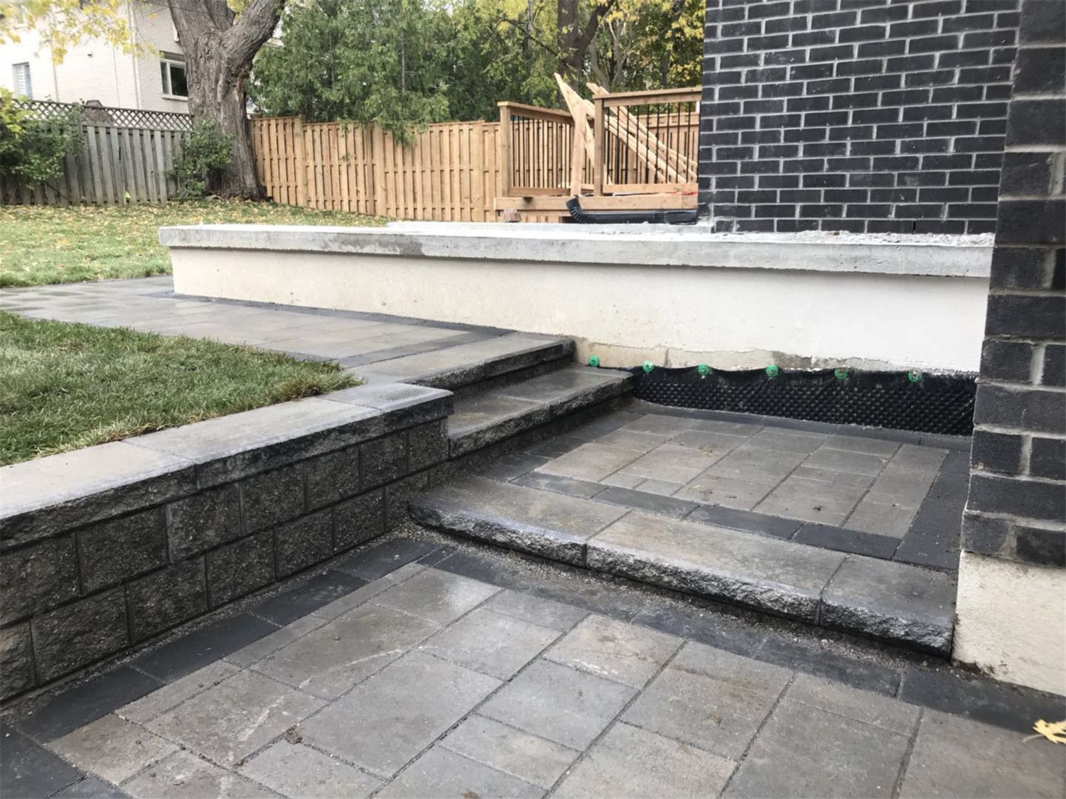 Toronto landscaping renovation featuring custom interlock patio steps and a retaining wall structure designed to create a multi-level backyard outdoor space. The durable paving stones and clean stone edging improve accessibility, drainage, and overall landscape functionality for a Toronto residential property.