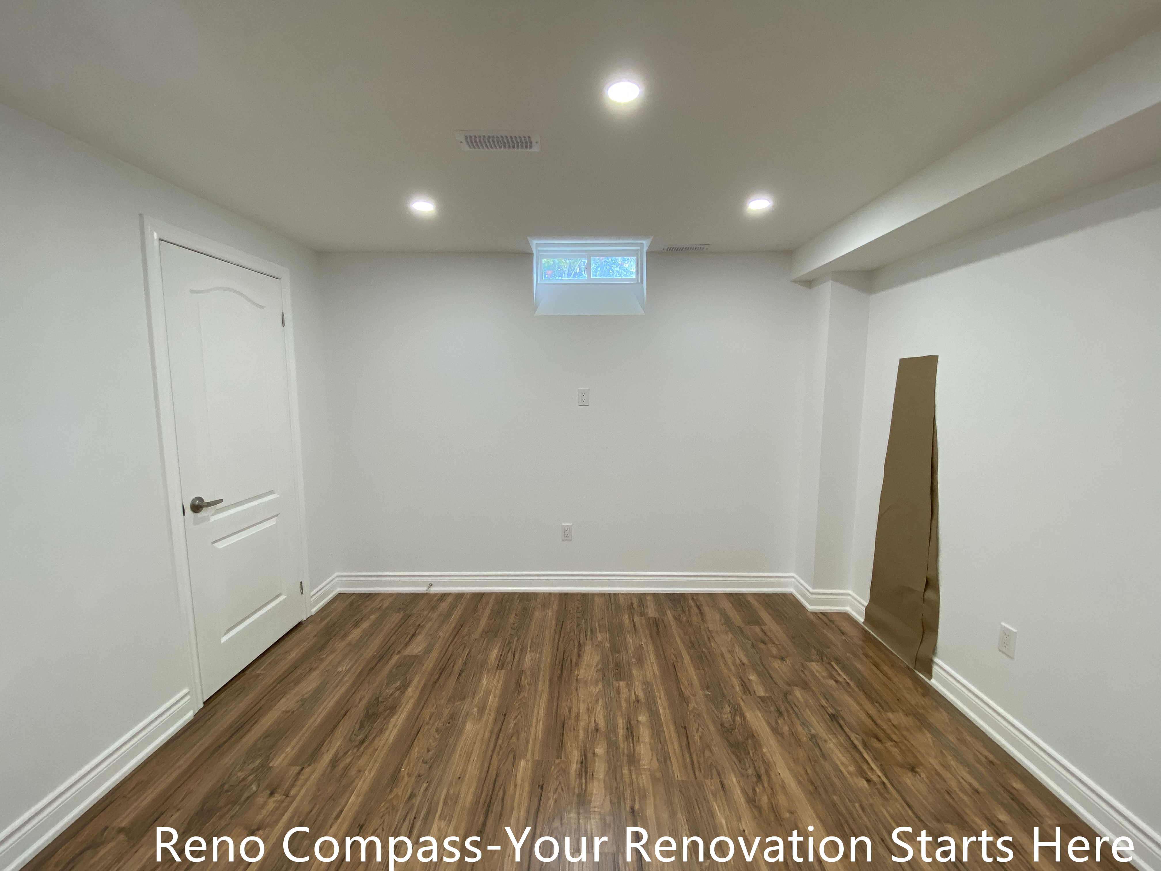This finished basement living area in Bradford showcases a clean, open layout designed for flexible everyday use. The space features durable wood-look flooring that adds warmth while remaining suitable for basement conditions. Evenly spaced recessed lighting enhances brightness and ceiling height, creating a comfortable environment for entertainment, home office use, or a family recreation area. Neutral wall finishes and simple door detailing allow the layout to adapt easily to different furnishing needs. As part of a complete Bradford basement renovation by Reno Compass Inc., this space reflects careful planning focused on functionality, long-term durability, and modern basement living standards.