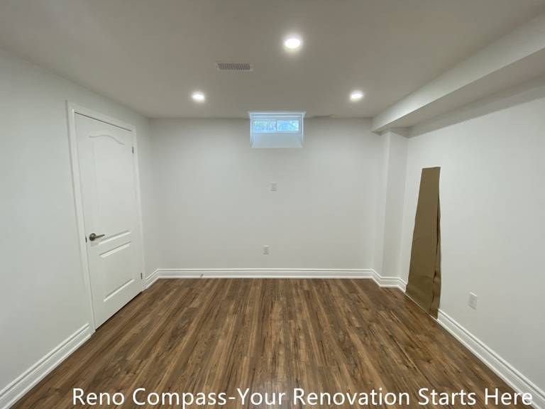 This finished basement living area in Bradford showcases a clean, open layout designed for flexible everyday use. The space features durable wood-look flooring that adds warmth while remaining suitable for basement conditions. Evenly spaced recessed lighting enhances brightness and ceiling height, creating a comfortable environment for entertainment, home office use, or a family recreation area. Neutral wall finishes and simple door detailing allow the layout to adapt easily to different furnishing needs. As part of a complete Bradford basement renovation by Reno Compass Inc., this space reflects careful planning focused on functionality, long-term durability, and modern basement living standards.