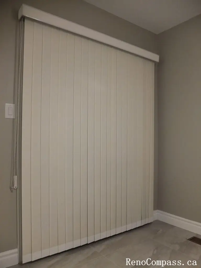 This Richmond Hill curtains installation features custom vertical blinds designed for a large sliding patio door, offering smooth operation, privacy, and effective light control. The neutral-toned vertical slats complement the modern interior and flooring, creating a clean and functional window treatment solution. Professionally measured and installed, these custom blinds enhance energy efficiency and everyday convenience while maintaining a sleek, contemporary appearance. A practical and stylish choice for homeowners in Richmond Hill and the Greater Toronto Area seeking expert curtain and blinds installation.