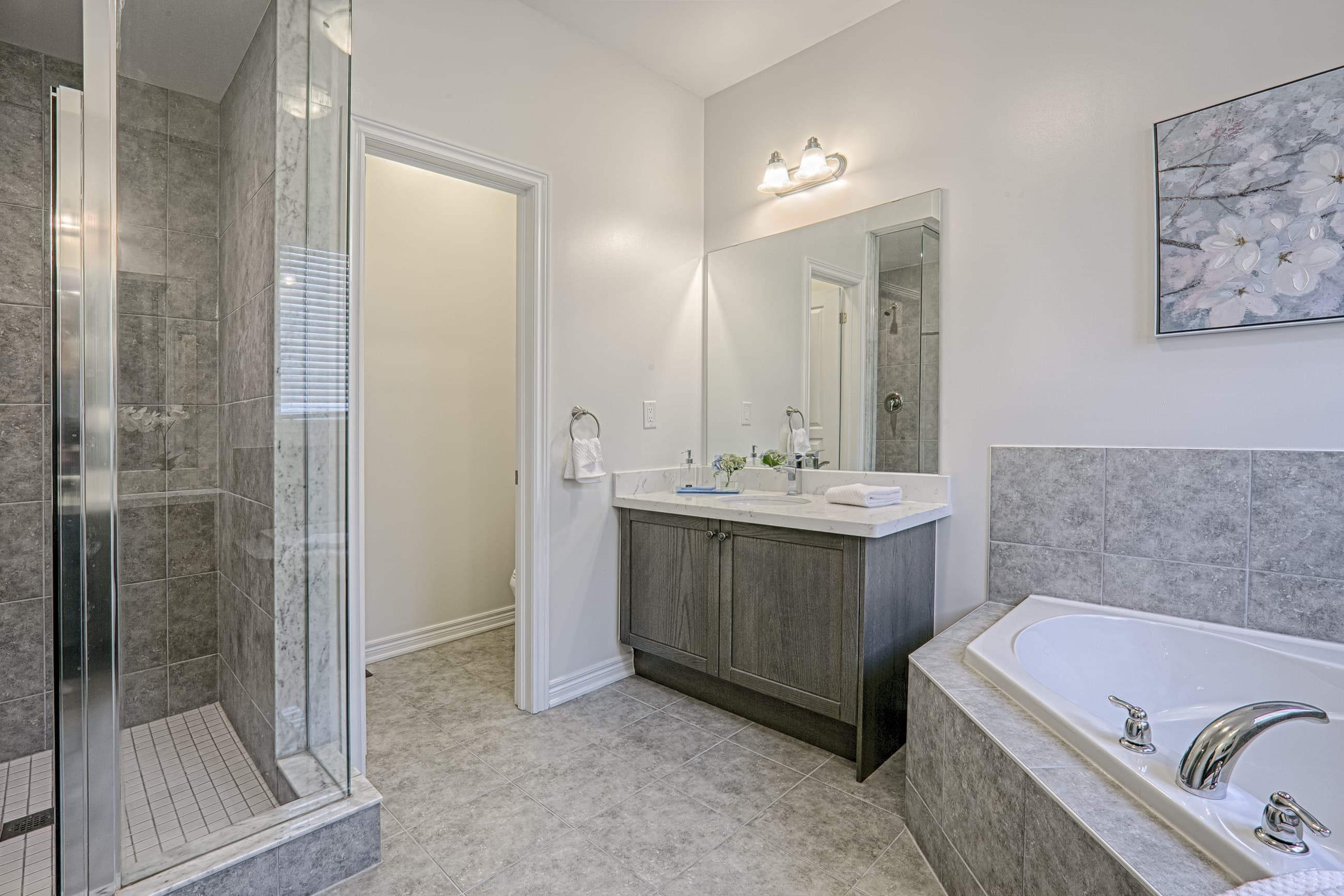This Toronto luxury master bathroom renovation features a spacious layout with a double vanity, premium stone countertops, and a built-in soaking tub surrounded by elegant tile finishes. The design includes modern lighting, large mirrors, and neutral tones that create a bright and relaxing spa-like environment. Completed by a professional Toronto renovation company, this bathroom project showcases high-quality craftsmanship, functional layout planning, and contemporary residential design tailored for modern comfort.