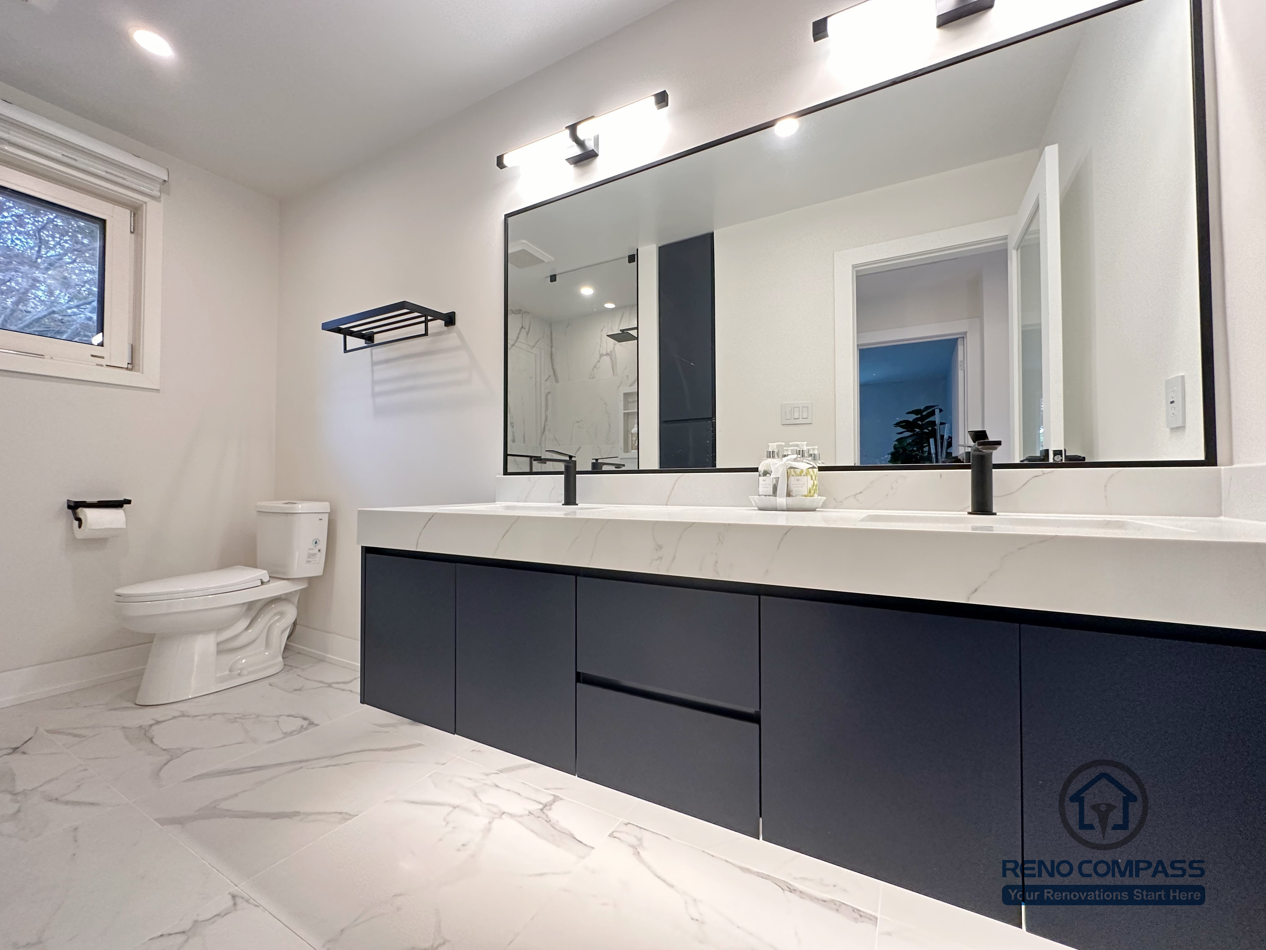 Spacious bathroom renovation in Toronto featuring a custom double-sink vanity, oversized mirror, modern wall-mounted lighting, matte black fixtures, and marble-look porcelain flooring. Designed and completed by a trusted Toronto renovation company with a focus on comfort, storage, and clean contemporary style.