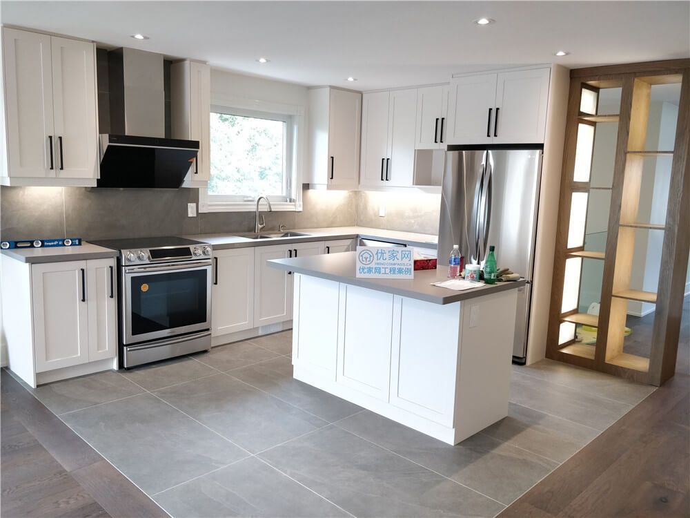 This North York interior renovation highlights an open-concept kitchen featuring a central island, custom white cabinetry, stainless steel appliances, and recessed ceiling lighting. The layout improves workflow and circulation while maintaining a clean, modern look that connects seamlessly with the surrounding living areas.