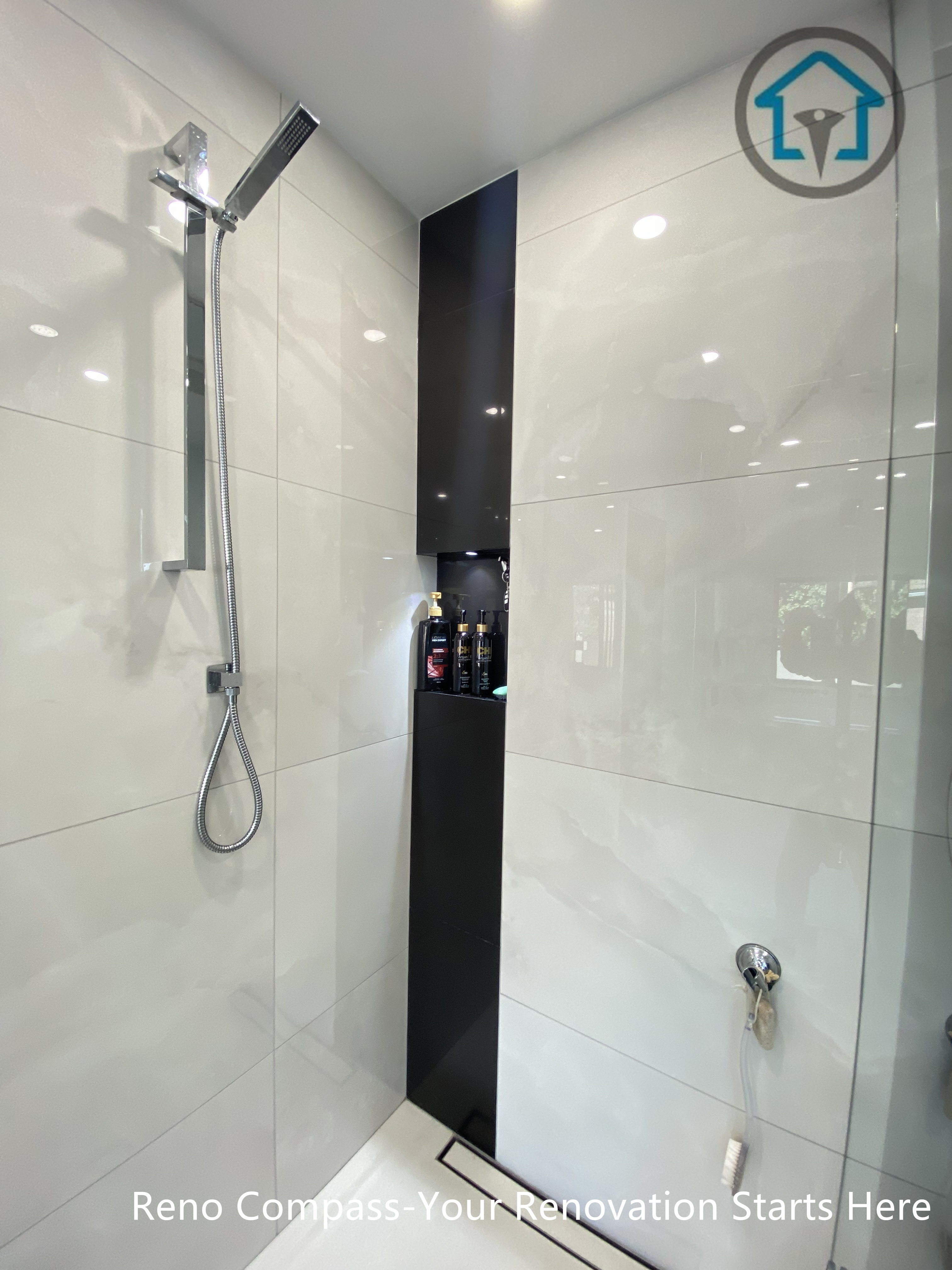 Close-up view of a modern shower renovation in Brampton featuring large-format glossy wall tiles, a built-in vertical shower niche for storage, and sleek chrome fixtures. The design highlights clean lines, moisture resistance, and practical detailing, completed by a professional Toronto renovation company.