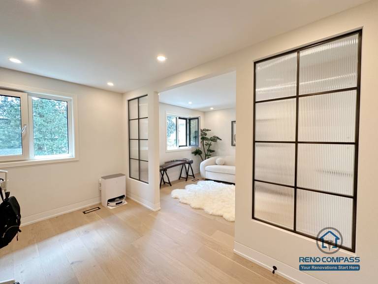 This Toronto interior renovation features light hardwood flooring, modern glass partition panels, and an open-concept layout that enhances natural light and spatial flow. The seamless flooring installation connects multiple living areas while maintaining subtle visual separation, showcasing refined craftsmanship ideal for contemporary home renovations in Toronto.