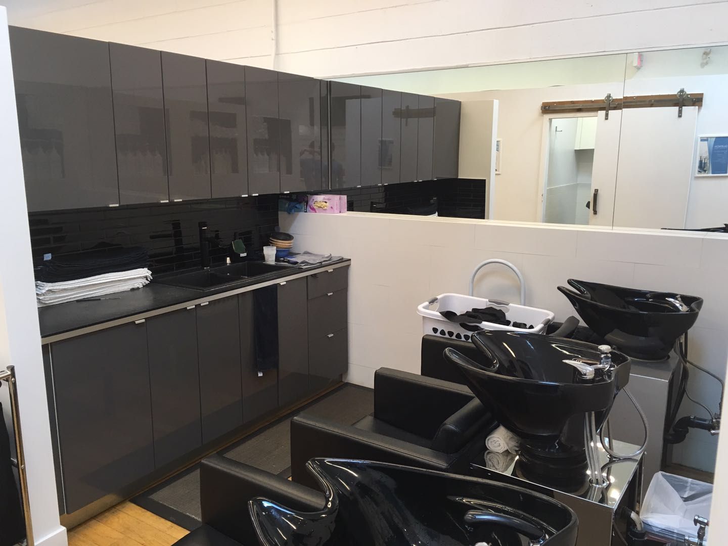 This Toronto spa renovation showcases a clean and modern hair washing area with professional salon shampoo stations, glossy black cabinetry, and an organized workspace layout. Designed for both efficiency and client comfort, the space reflects a high-end commercial interior built for daily salon operations.