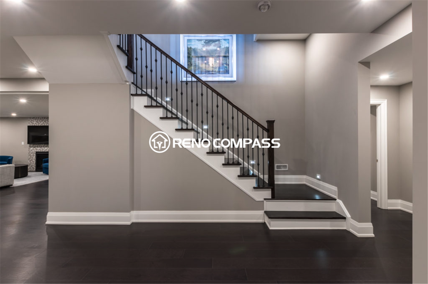 Professional basement renovation in Toronto featuring a modern staircase with iron railings, recessed lighting, and dark hardwood flooring. This well-designed basement layout improves accessibility and creates a bright, open living space, completed by a trusted Toronto renovation company, Reno Compass Inc.