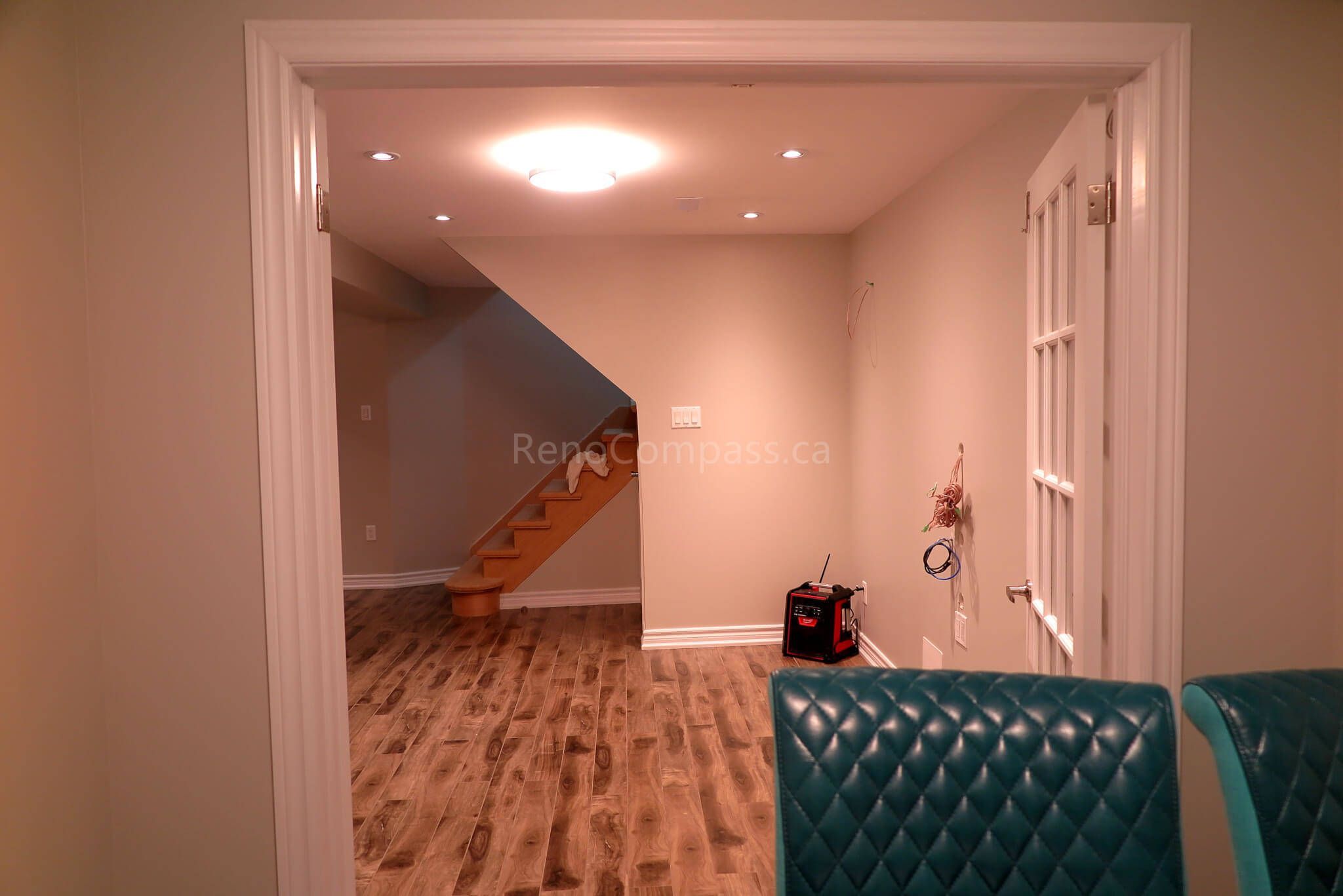 After photo from a Richmond Hill basement renovation featuring an open-concept layout with recessed lighting, wood-style vinyl flooring, and a modern staircase. The design creates a warm and functional living or entertainment area perfect for family use.