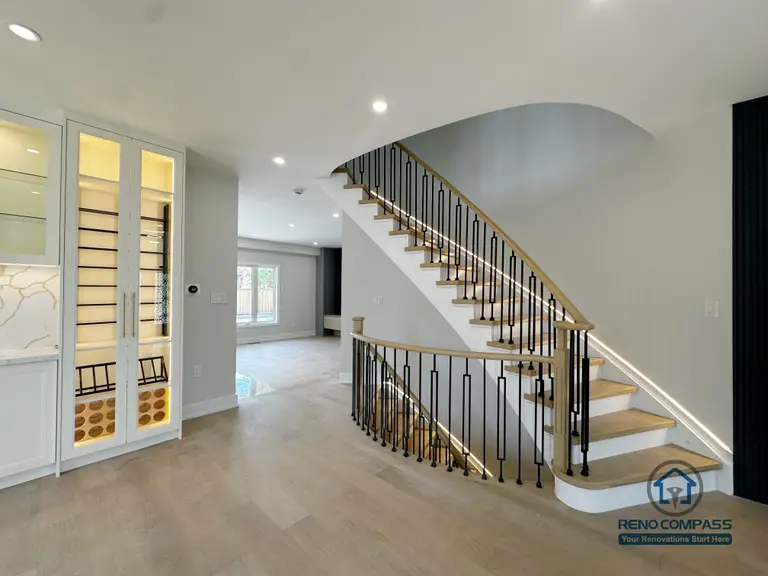 This image showcases the staircase and open living area from a Markham interior renovation project, where spatial flow and visual continuity were key design priorities. The staircase features light wood treads paired with black metal railings, creating a clean contrast that adds definition without overwhelming the space. Integrated LED lighting along the steps enhances both safety and atmosphere.

The open layout allows natural light to travel freely across the main floor, visually connecting the staircase, adjacent cabinetry, and living areas. Neutral finishes and consistent material selections help unify the different zones while maintaining a calm, modern aesthetic.

Careful attention to proportions, circulation, and lighting ensures the space feels open yet well-structured. This design reflects Reno Compass’s approach to interior renovations—balancing architectural clarity, everyday functionality, and refined detailing for Markham homes.