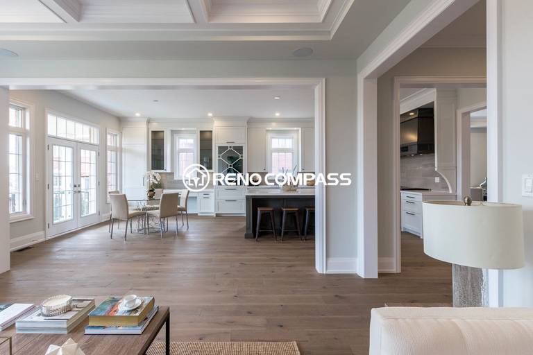 This Newmarket kitchen renovation showcases a spacious open-concept design with custom white cabinetry, a large quartz island, engineered wood flooring, and modern lighting. The kitchen flows seamlessly into the dining area, creating a bright and functional space for everyday living and entertaining. Completed by a trusted Toronto renovation company, Reno Compass Inc., the project highlights elegant design and high-quality craftsmanship.