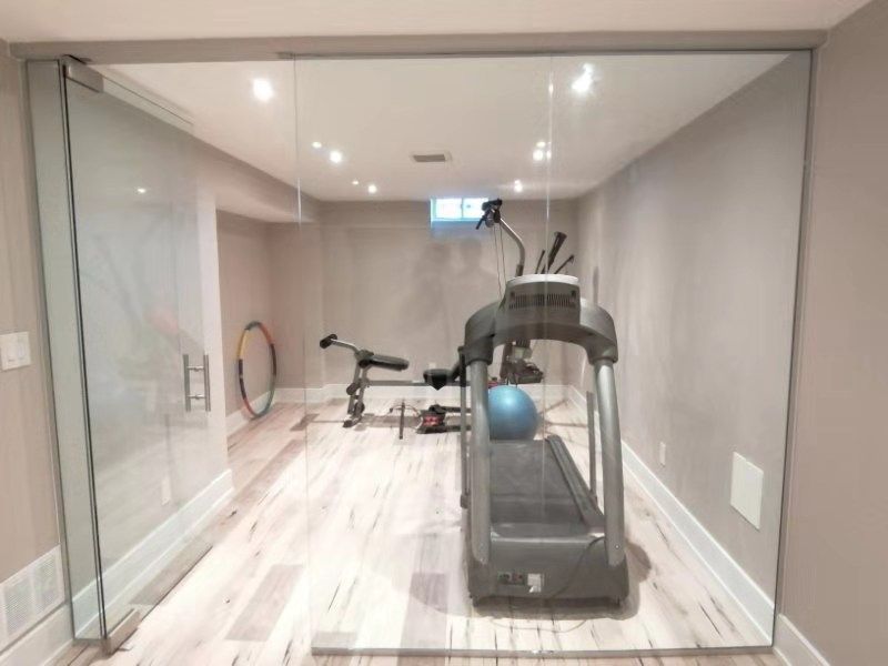 This Richmond Hill interior partial renovation showcases a modern basement home gym upgrade featuring a full glass partition wall, recessed ceiling lighting, and durable light-tone flooring. The space was redesigned to create a bright and functional fitness area while maintaining a clean, contemporary interior style. This basement renovation enhances usability and adds lifestyle value to the home, providing a dedicated workout space with improved lighting, layout, and finishing details. Completed by Reno Compass, this project highlights professional interior remodeling services across Richmond Hill and the Greater Toronto Area.