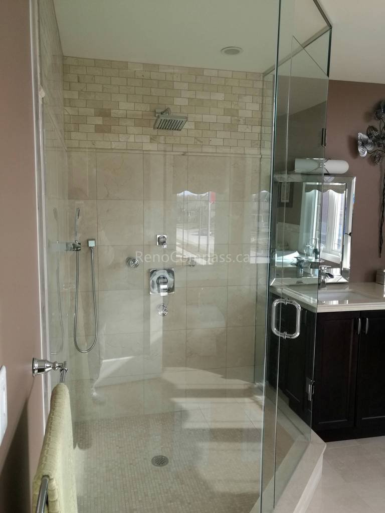 This image features a walk-in glass shower completed as part of a Toronto interior renovation project. The shower is finished with neutral-toned wall tiles and a mosaic tile floor, creating a clean and cohesive look. A frameless glass enclosure enhances openness while allowing natural light to flow through the space. Integrated fixtures and a ceiling-mounted showerhead add both functionality and modern comfort. This bathroom renovation highlights careful detailing, durable materials, and high-quality craftsmanship tailored to Toronto residential interiors.