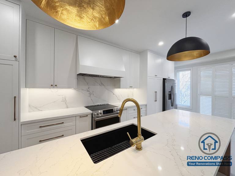 This Oakville kitchen renovation highlights the primary cooking zone, featuring a marble-style backsplash, clean-lined cabinetry, and a well-positioned island sink that supports efficient meal preparation. The coordinated surfaces and fixtures create a seamless transition between cooking and prep areas, while pendant lighting provides focused illumination without disrupting visual balance. Completed by Reno Compass, this kitchen design emphasizes clarity, functionality, and long-term practicality for everyday use in an Oakville home.