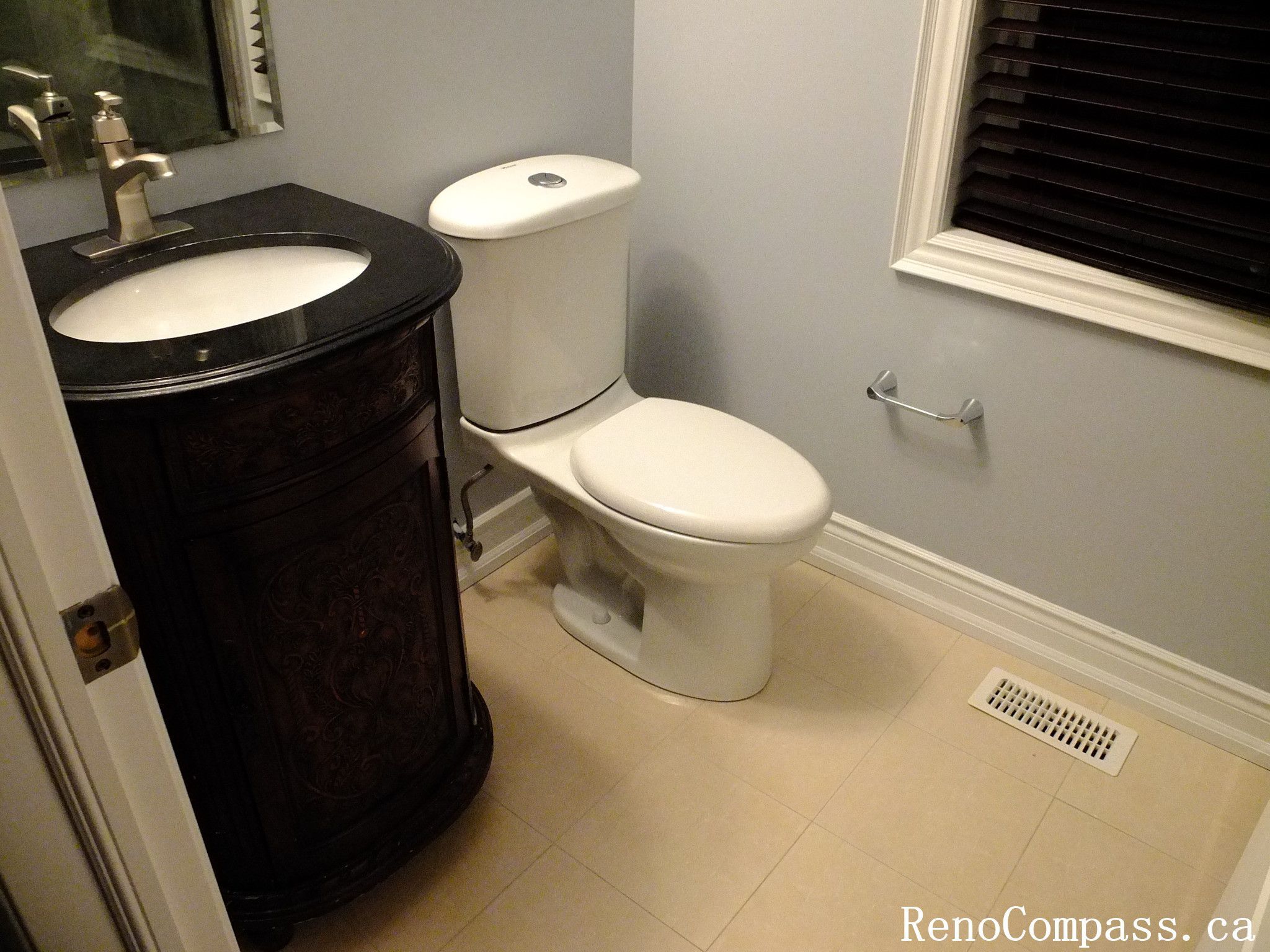 Elegant powder room renovation in Richmond Hill featuring a dark wood vanity with marble countertop, modern toilet installation, and beige ceramic tile flooring. A stylish blend of functionality and luxury by RenoCompass.ca interior renovation experts.