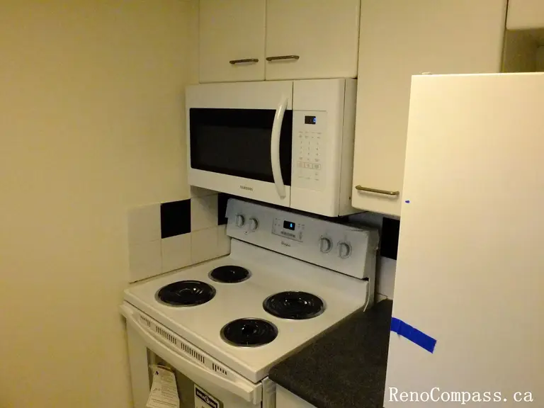 This image shows the original kitchen appliance area of a Toronto condominium before renovation. The space includes a traditional electric stove, over-the-range microwave, and surrounding cabinetry. As part of a Toronto interior renovation project, the kitchen appliances and layout were reviewed for upgrades to improve efficiency, modern design, and overall kitchen functionality.