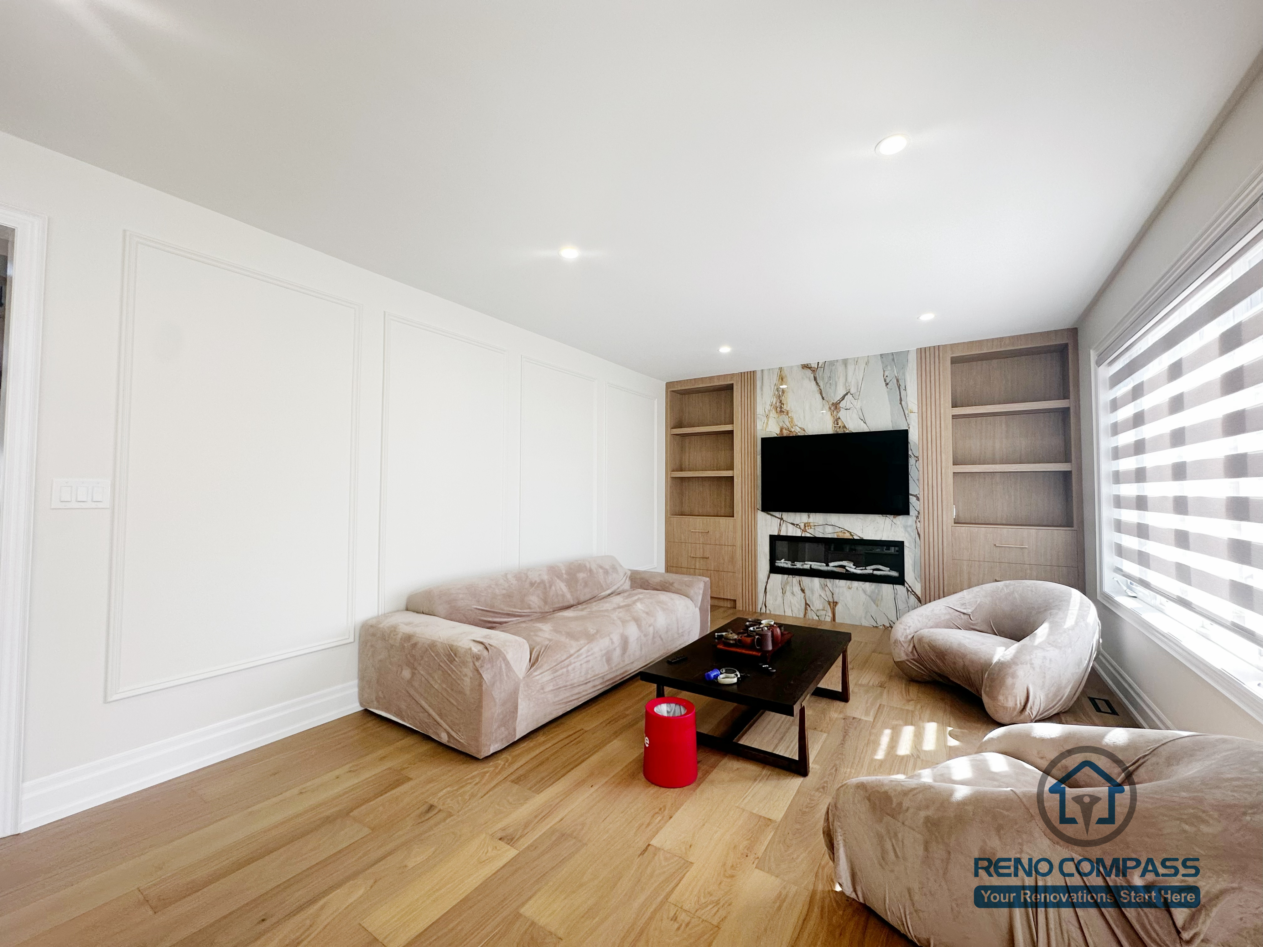 This image showcases a completed flooring renovation combined with a custom feature TV wall as part of a North York flooring and stair project. The space features wide-plank hardwood flooring that adds warmth and continuity throughout the living area. A custom-designed TV feature wall with built-in shelving and stone accent panels creates a strong focal point while maintaining a clean, modern aesthetic. This renovation demonstrates how coordinated flooring installation and feature wall design can enhance both functionality and visual impact in North York homes.