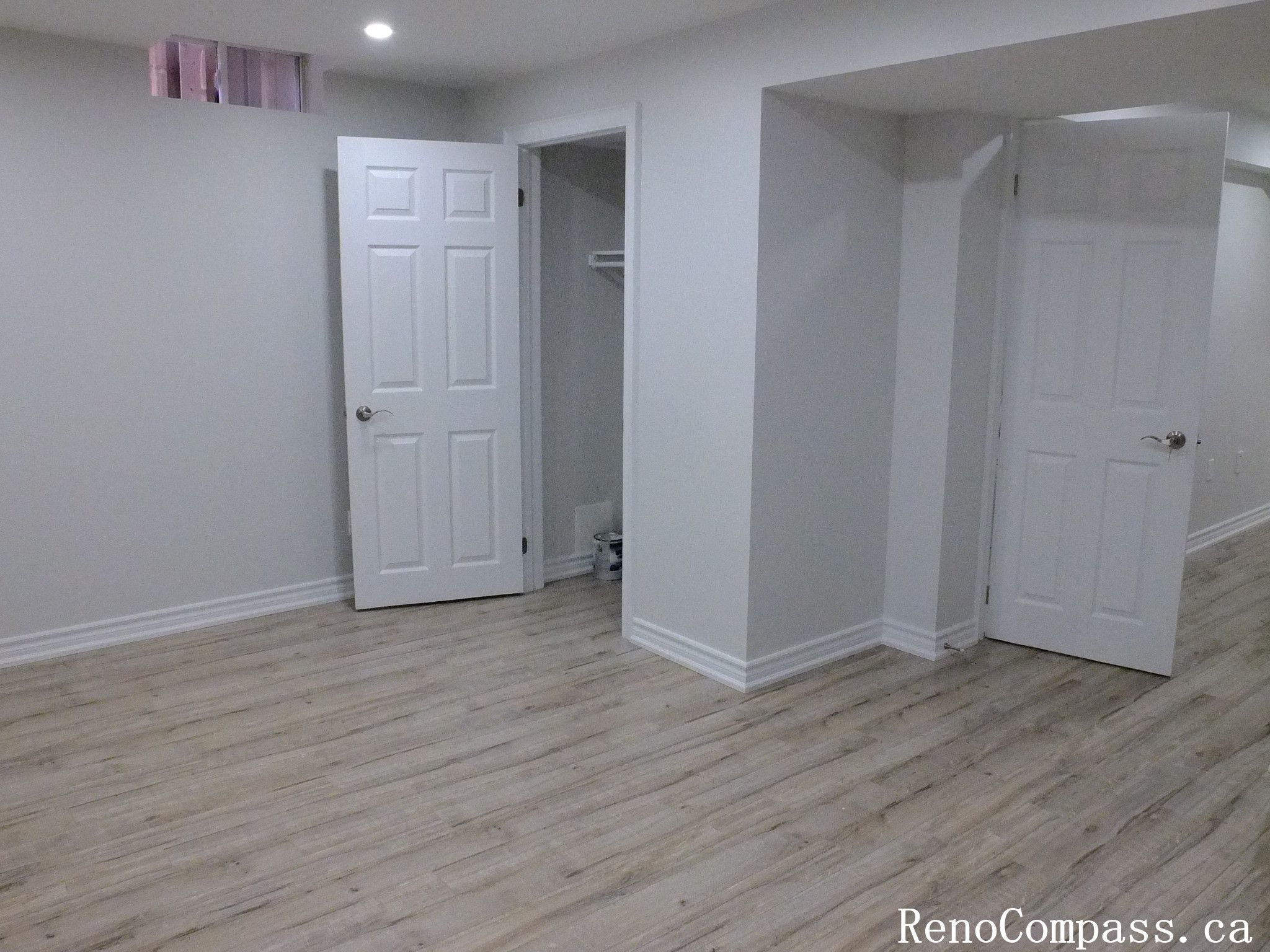 A beautifully finished basement renovation in Richmond Hill featuring light wood floors, recessed lighting, and modern white doors. This space highlights a clean, open layout perfect for a family entertainment area or guest suite, designed and completed by Reno Compass.