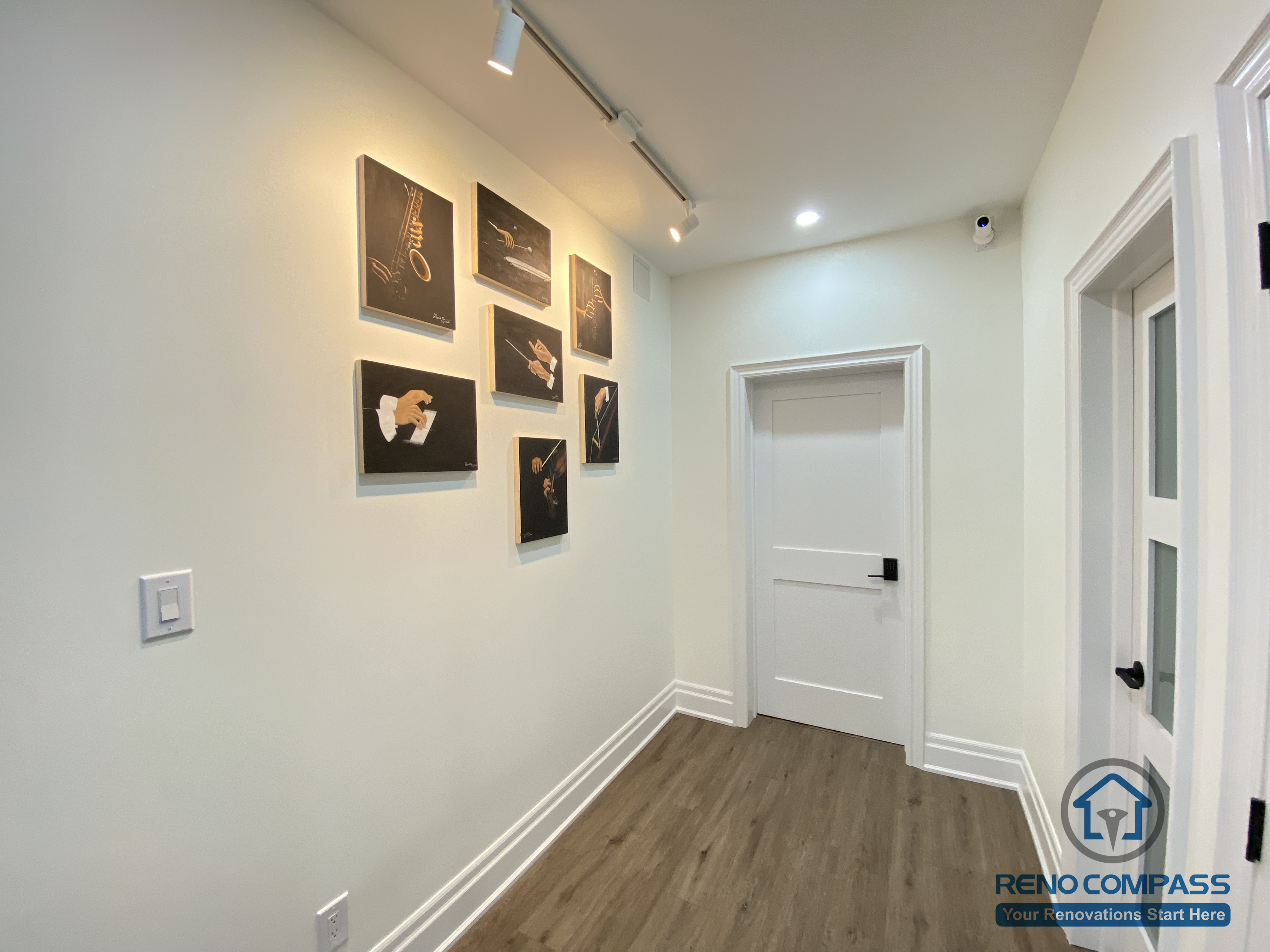 This Oakville basement renovation features a refined gallery-style hallway designed to showcase artwork with focused track lighting. Clean wall surfaces, warm wood flooring, and minimalist trim details create a calm backdrop that highlights visual displays while maintaining smooth circulation. Recessed and track lighting work together to enhance depth and atmosphere without overwhelming the space. As a professional Toronto renovation company, Reno Compass designs basement corridors that combine aesthetics, lighting control, and functionality, transforming transitional areas into intentional design features.