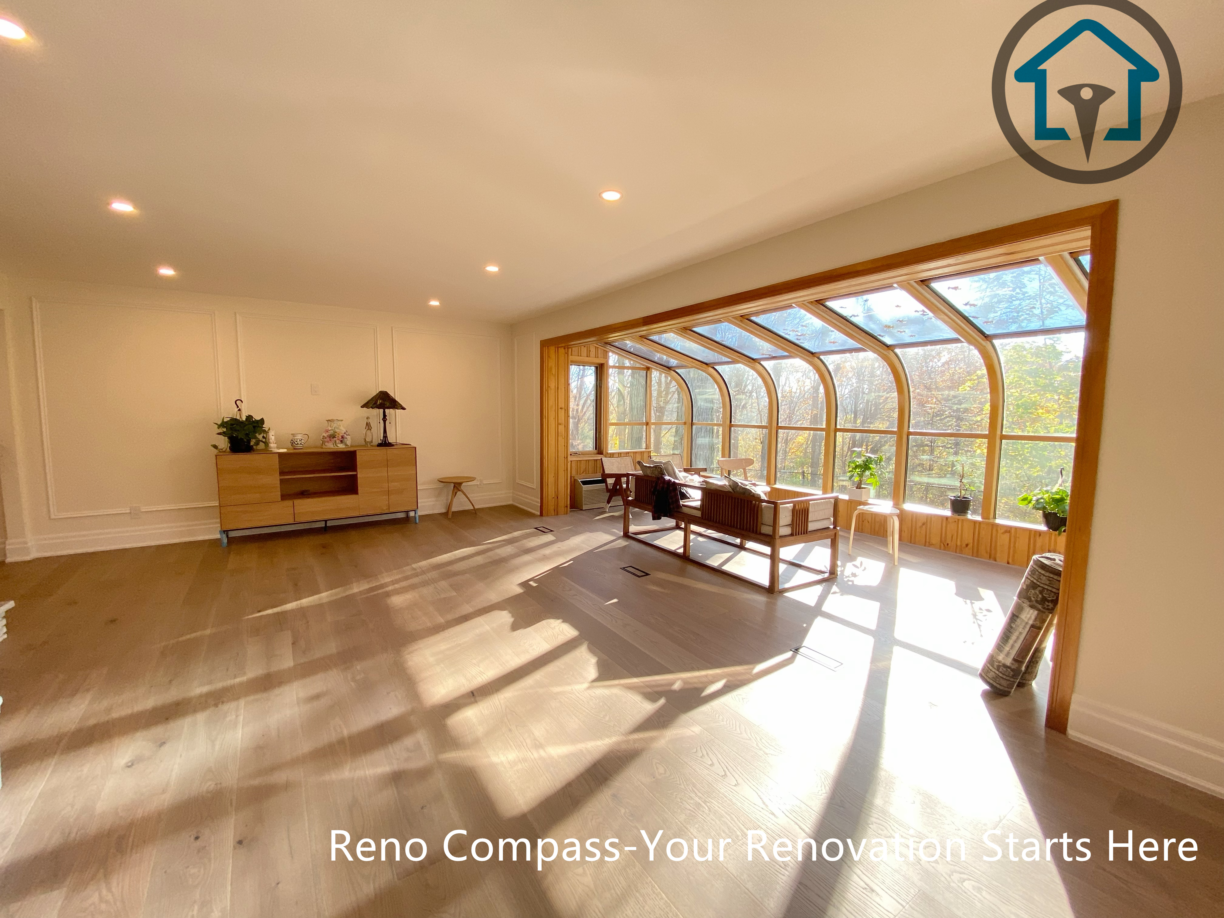 This North York house interior renovation features a bright open living area seamlessly connected to a sunroom-style extension. Large curved windows bring in abundant natural light, enhancing the sense of openness and visual connection to the outdoors. Wood flooring and recessed lighting create a warm, comfortable environment ideal for everyday living and relaxation.