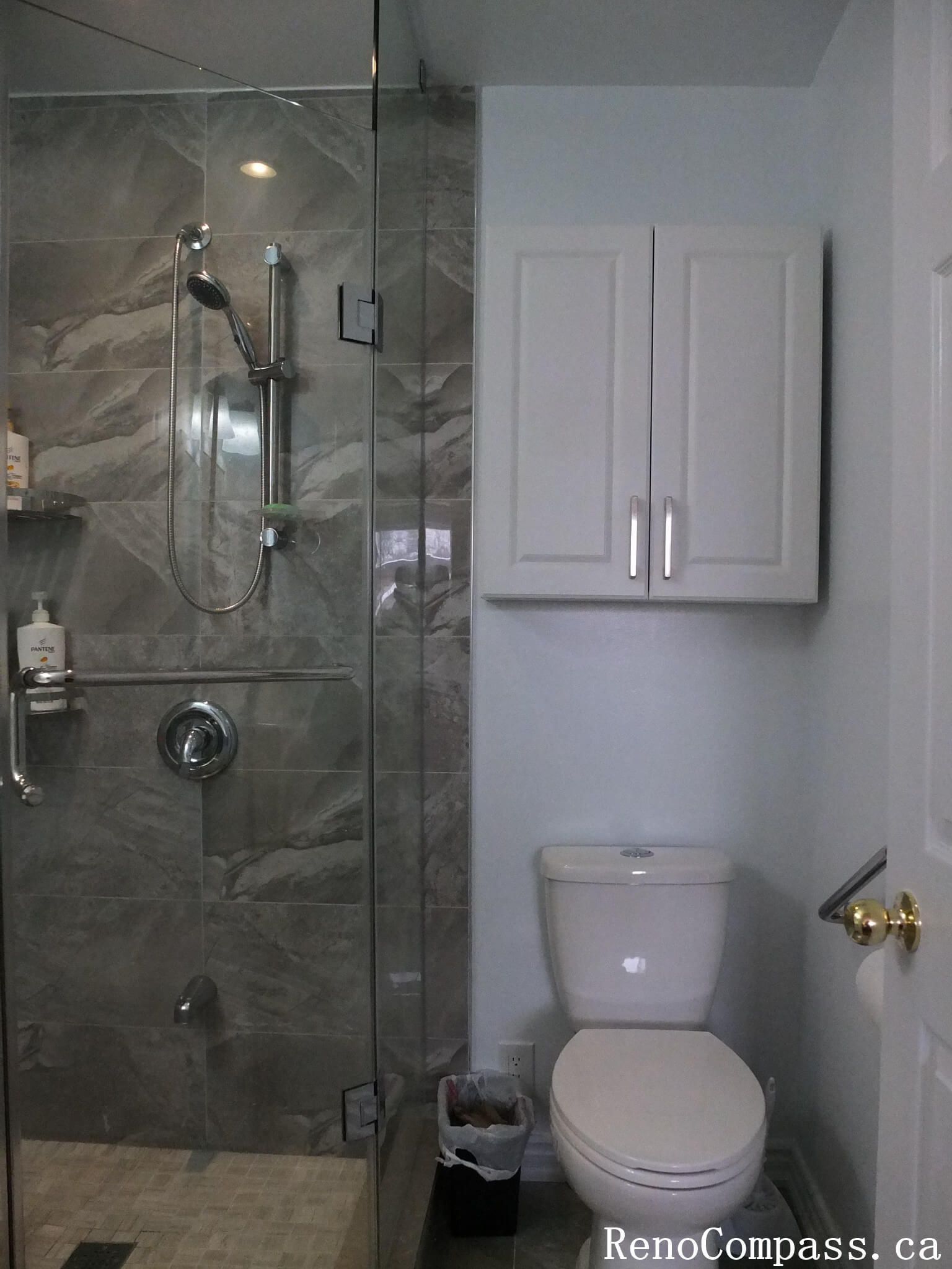 Bathroom renovation in North York featuring a frameless glass shower, marble-look wall tiles, wall-mounted storage cabinet, and compact layout design. This Toronto interior renovation focuses on efficient space planning, clean finishes, and practical upgrades suitable for small to mid-size residential bathrooms.