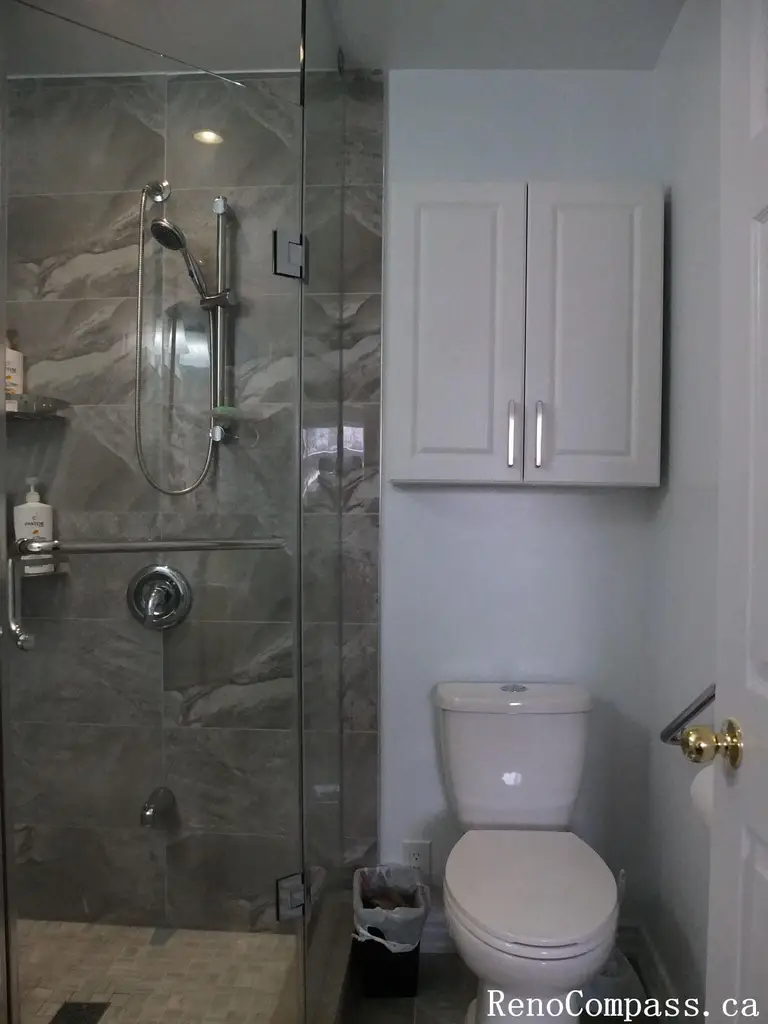 Bathroom renovation in North York featuring a frameless glass shower, marble-look wall tiles, wall-mounted storage cabinet, and compact layout design. This Toronto interior renovation focuses on efficient space planning, clean finishes, and practical upgrades suitable for small to mid-size residential bathrooms.