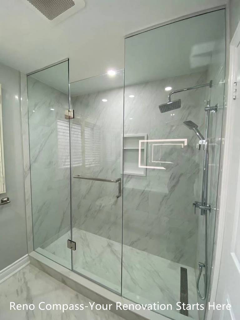 This Oakville interior renovation features a modern walk-in shower designed with frameless glass panels and full-height marble-look porcelain tiles. The clean glass enclosure enhances visual openness while allowing natural and artificial light to flow through the space. A rain shower system, wall-mounted hand shower, and built-in niche provide both comfort and functionality. The minimalist layout and neutral stone tones create a calm, spa-inspired bathroom environment that is durable, easy to maintain, and ideal for long-term residential use. This project reflects the precision detailing and modern design standards expected from a professional Toronto renovation company.