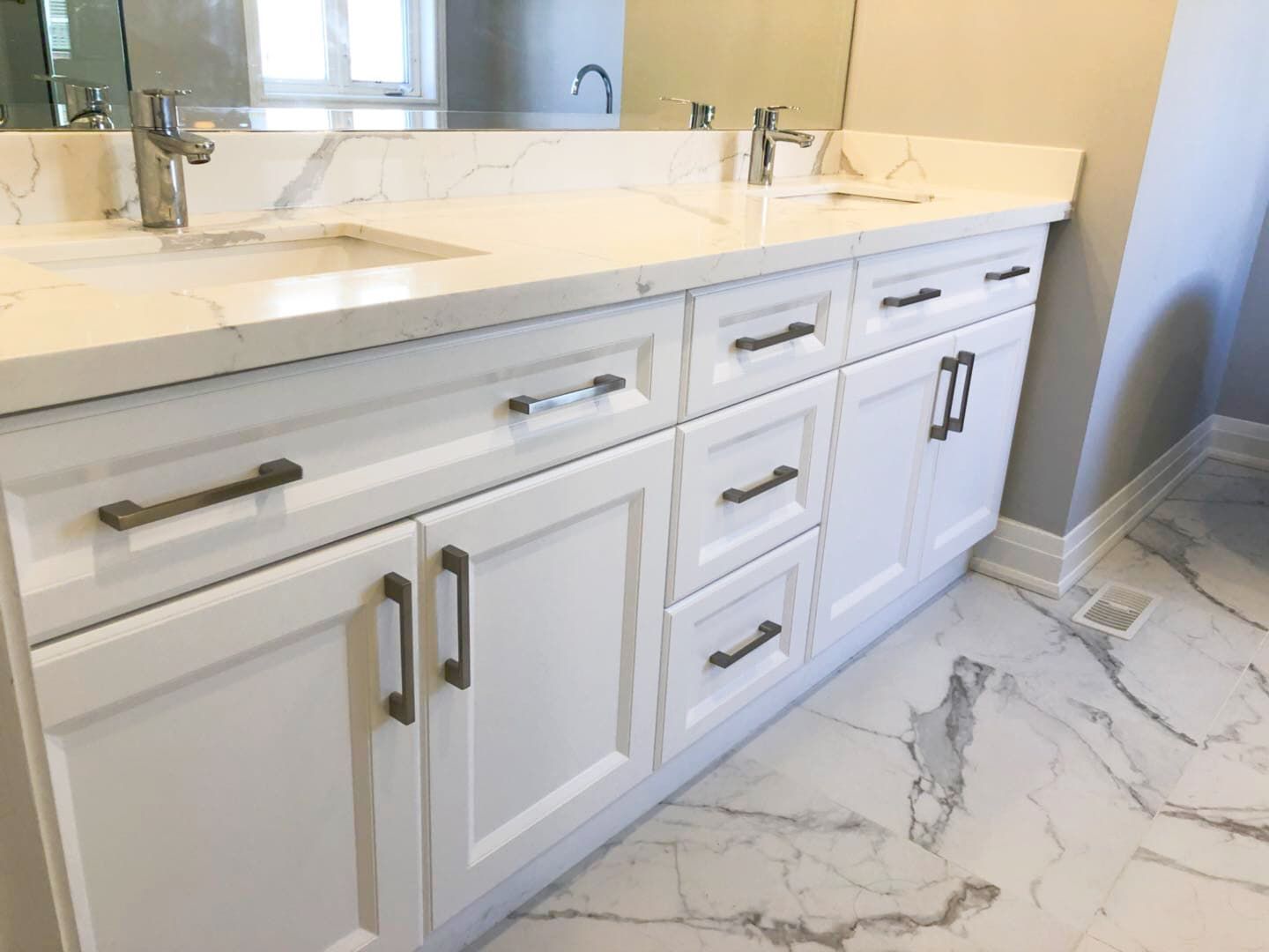 This Richmond Hill bathroom renovation features a modern double-sink vanity with custom white shaker cabinetry, quartz countertops, and sleek black hardware. The upgraded layout improves both storage and daily functionality while maintaining a clean and timeless aesthetic. Large-format marble-style flooring and a glass shower enclosure enhance the luxury feel, creating a bright and elegant space ideal for modern family living. Professionally completed by a trusted Toronto renovation company, this project combines durability, comfort, and refined design for long-term use.