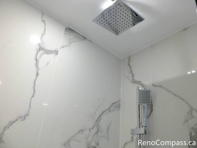 This Richmond Hill bathroom renovation features a modern ceiling-mounted rainfall shower head paired with a handheld shower system and marble-look porcelain wall tiles. Completed by a professional Toronto renovation company, the upgraded shower design delivers a spa-like experience with clean lines, efficient water flow, and durable contemporary finishes.