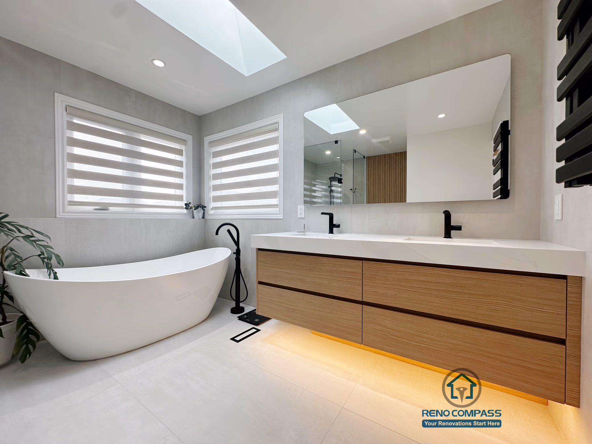 A modern curbless bathroom renovation completed by Reno Compass in Markham, Toronto.
This design features a freestanding bathtub placed by natural light, a floating double-sink vanity with warm wood tones, and soft under-cabinet lighting that enhances both functionality and atmosphere.