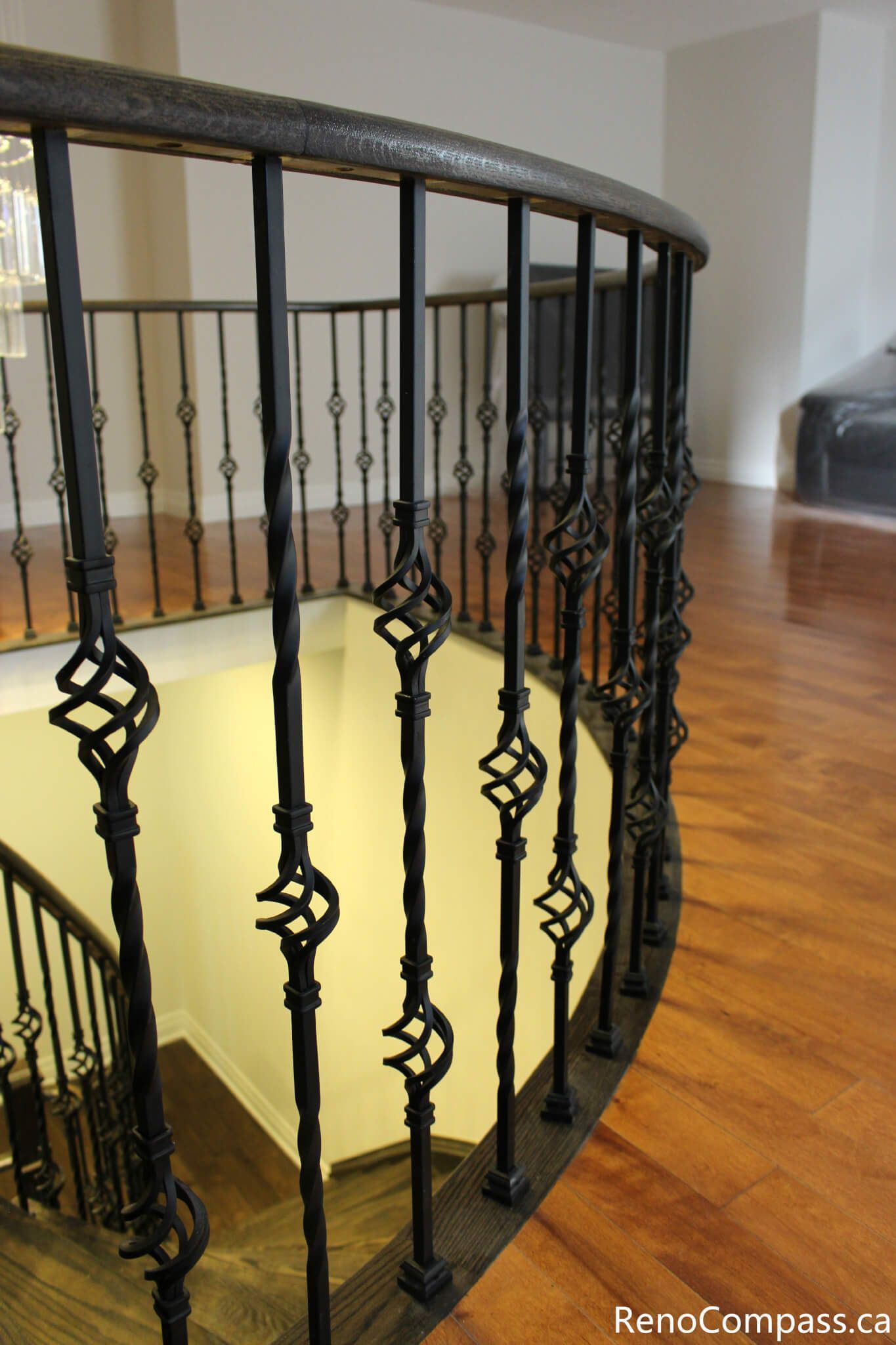 This Mississauga interior renovation showcases a custom curved iron stair railing paired with rich hardwood flooring and clean modern wall finishes. The detailed railing design enhances both safety and architectural elegance, creating a refined open stairwell feature. Completed by a trusted Toronto renovation company, Reno Compass Inc., this project highlights precision craftsmanship and high-quality interior finishing.