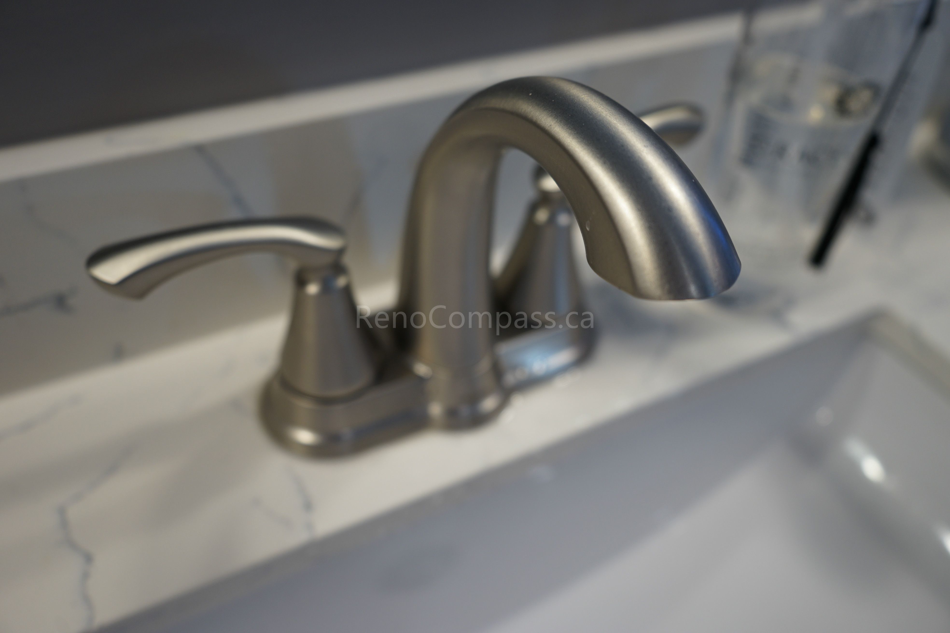 Close-up of a modern brushed nickel bathroom faucet installed on a marble countertop as part of a Markham bathroom renovation. The upgraded sink fixtures combine durability, functionality, and elegant design, adding a refined finishing touch to this clean and contemporary bathroom space.