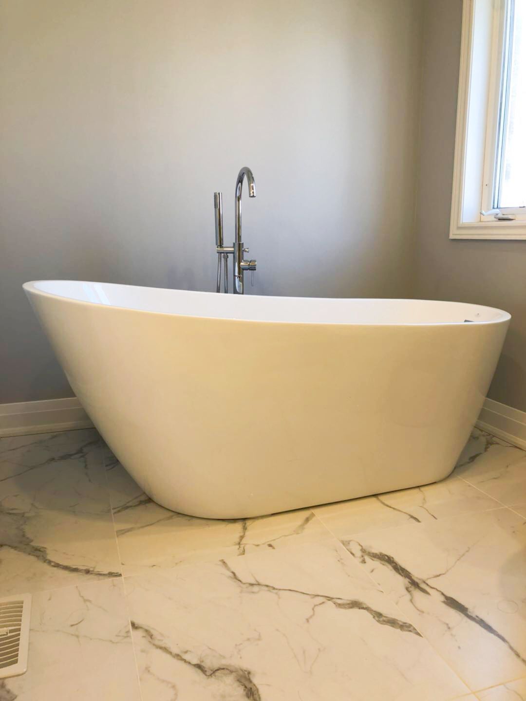 This Richmond Hill bathroom renovation features a modern freestanding soaking tub paired with marble-style flooring and a sleek floor-mounted faucet. The upgraded layout creates a spa-inspired atmosphere while maximizing comfort and visual space. A contemporary smart toilet and neutral color palette enhance both functionality and elegance. Completed by an experienced Toronto renovation company, this bathroom transformation combines luxury design, durable materials, and everyday convenience for a refined modern home.