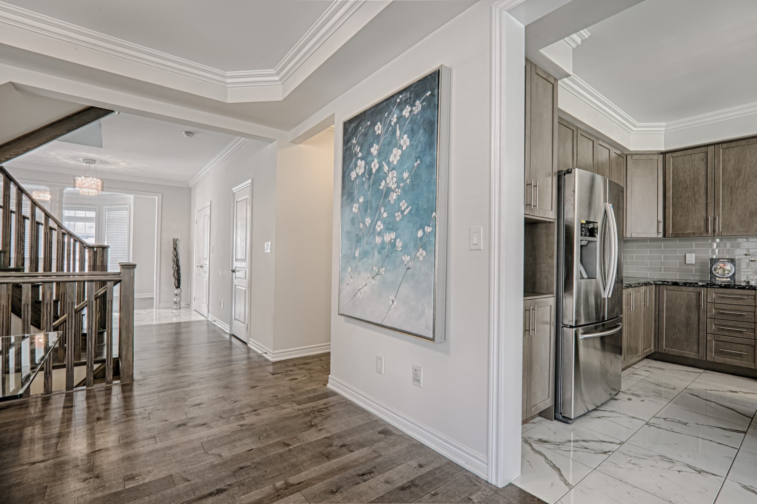 This Toronto interior renovation showcases a bright and elegant hallway and open-concept layout connecting the staircase, living areas, and modern kitchen. The space features premium hardwood flooring, refined ceiling details, and seamless transitions between rooms that enhance both functionality and visual flow. Completed by a professional Toronto renovation company, this project highlights quality craftsmanship, contemporary design, and practical layout planning tailored for modern family living.