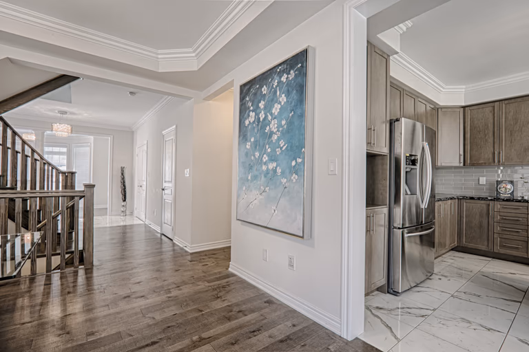 This Toronto interior renovation showcases a bright and elegant hallway and open-concept layout connecting the staircase, living areas, and modern kitchen. The space features premium hardwood flooring, refined ceiling details, and seamless transitions between rooms that enhance both functionality and visual flow. Completed by a professional Toronto renovation company, this project highlights quality craftsmanship, contemporary design, and practical layout planning tailored for modern family living.