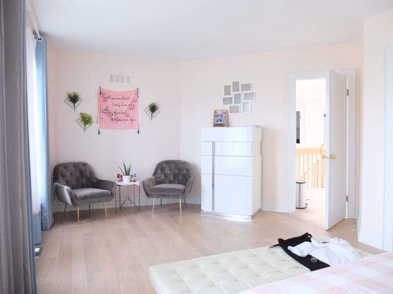 This image showcases a bright and airy bedroom as part of a Richmond Hill interior renovation project. The space features light wood flooring, soft neutral wall colors, and a clean, minimalist layout that enhances openness and comfort. Natural light flows through large windows, while modern furniture placement improves functionality. This bedroom renovation reflects the thoughtful space planning and finishing quality delivered by a professional Toronto renovation company.