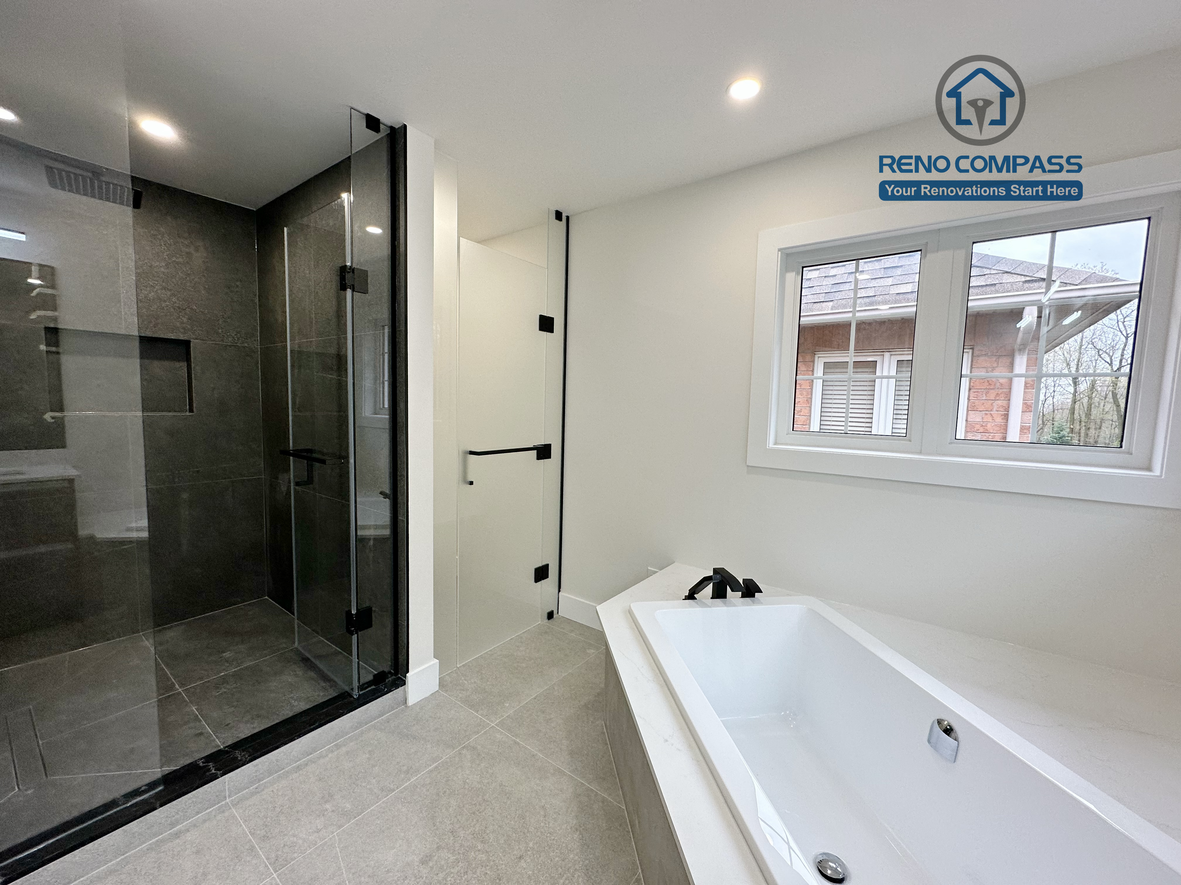 Modern bathroom renovation in Richmond Hill featuring a frameless glass shower with dark tile finishes alongside a built-in soaking tub, creating a balanced layout that combines functionality, comfort, and contemporary design.