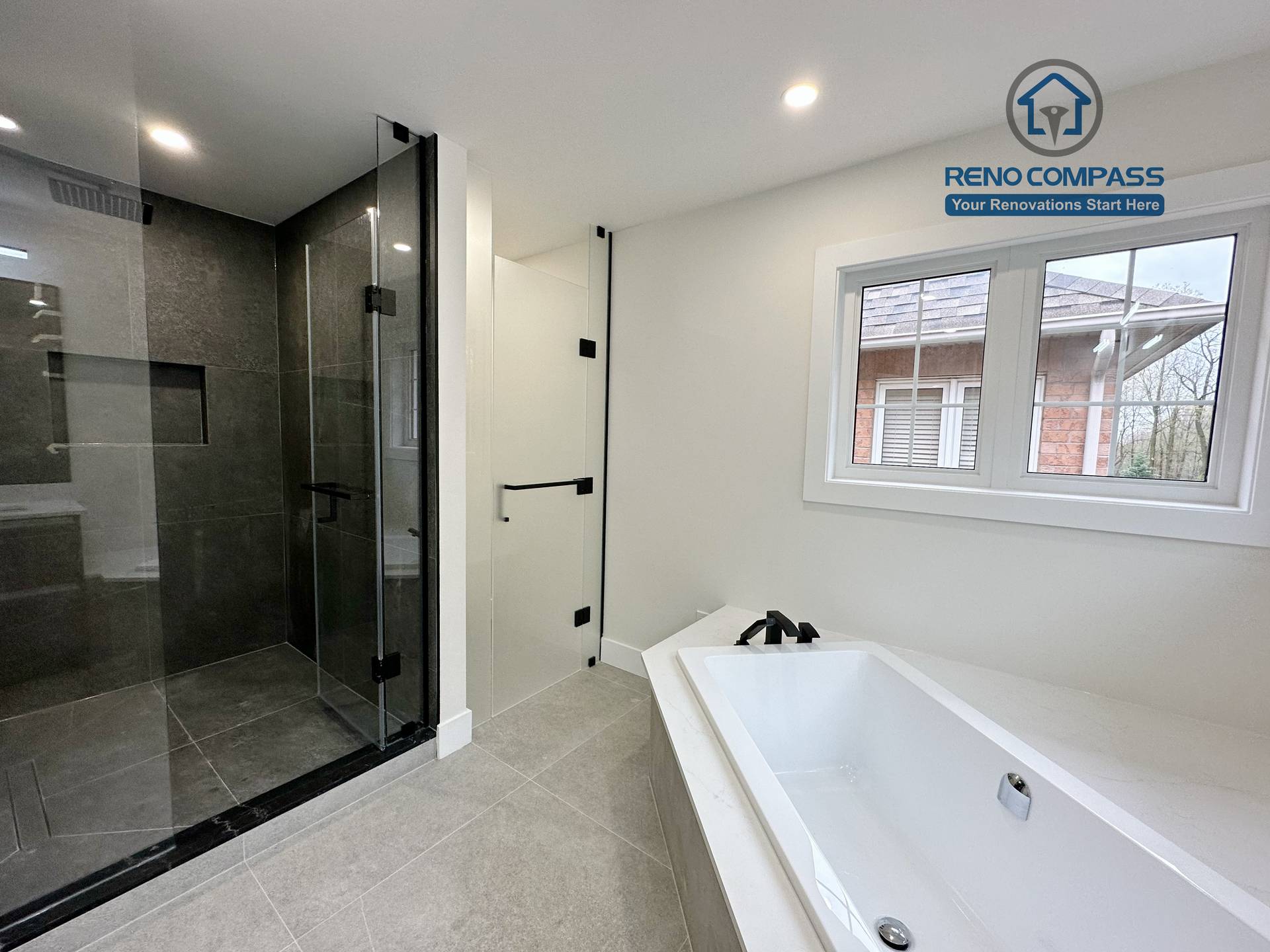 Modern bathroom renovation in Richmond Hill featuring a frameless glass shower with dark tile finishes alongside a built-in soaking tub, creating a balanced layout that combines functionality, comfort, and contemporary design.