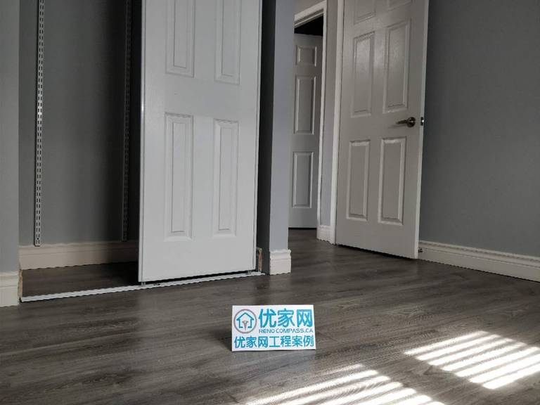 Bedroom interior renovation in Ajax featuring durable grey vinyl plank flooring, freshly painted walls, and updated white interior doors and baseboards. The modern flooring upgrade enhances the room’s brightness and functionality, completed by a professional Toronto renovation company specializing in residential interior improvements.