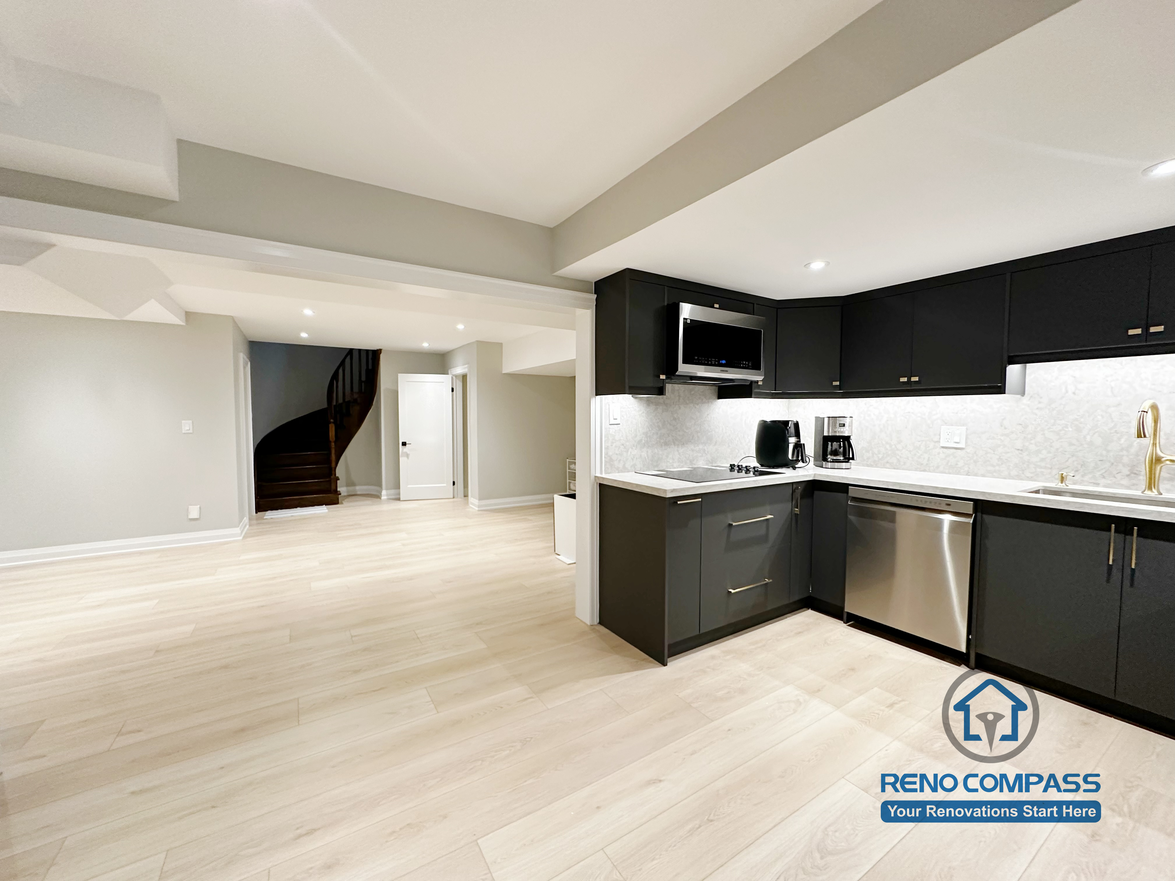 Basement renovation in Richmond Hill featuring a modern kitchenette with matte black cabinetry, stainless steel appliances, quartz-style countertops, and efficient space planning for daily use.