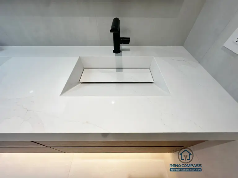This Markham bathroom renovation highlights a minimalist integrated sink design paired with a matte black faucet and seamless quartz countertop.
The clean geometry and refined detailing emphasize durability, ease of maintenance, and modern elegance.
